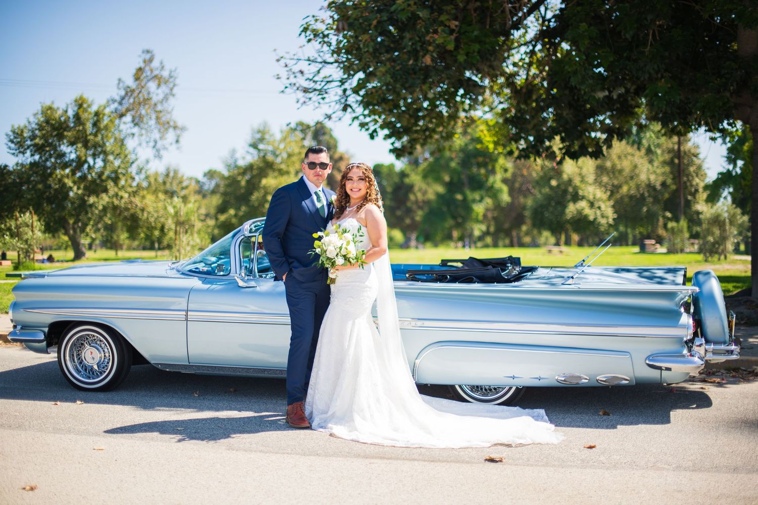Wedding couple poses next to a vintage silver Cadillac on their special day Legg Lake Park, Whittier Narrows Recreation Area.