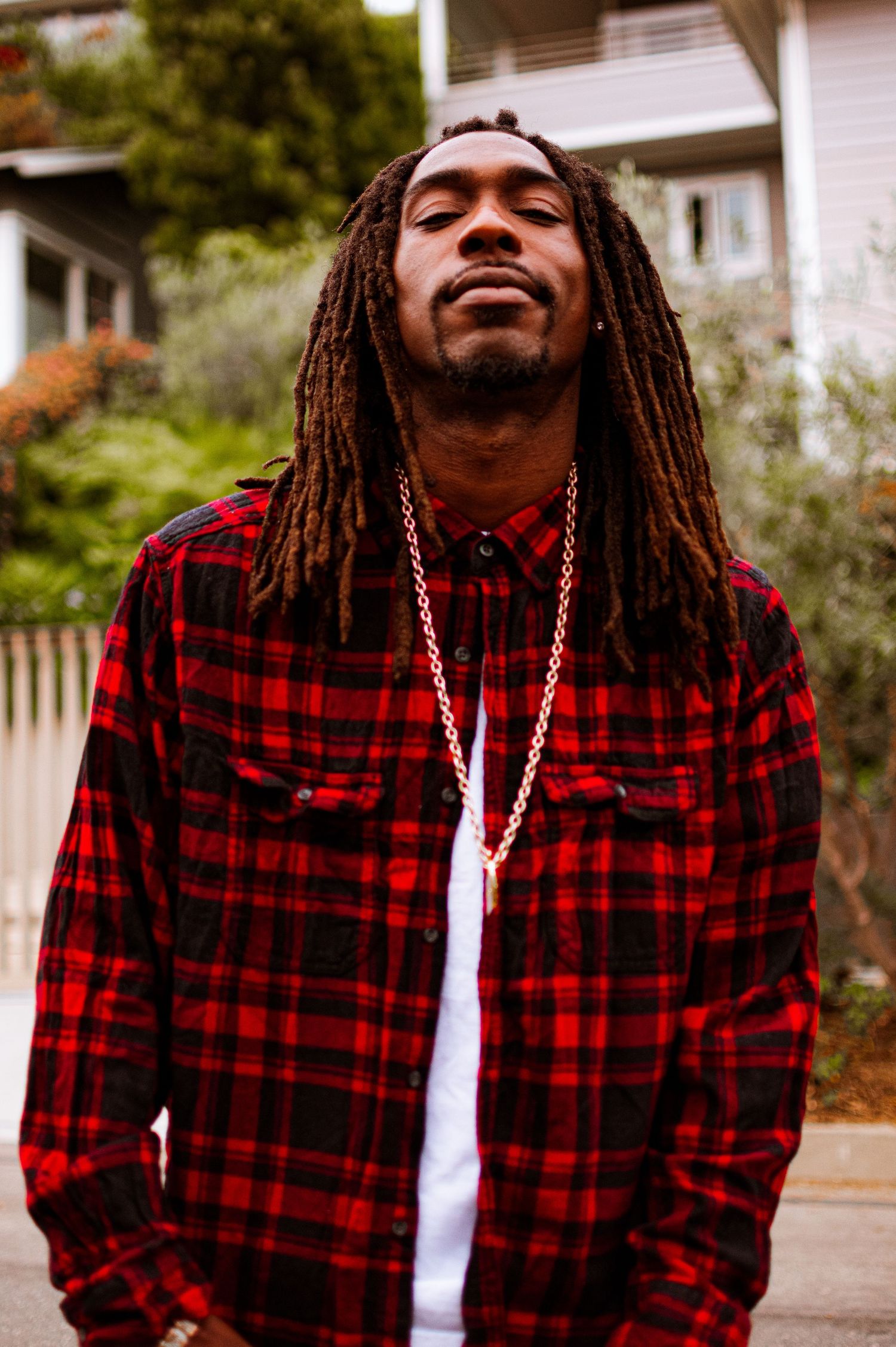 A series of five progressive shots showing someone in a red plaid flannel shirt and dreadlocks expressing joy outdoors.