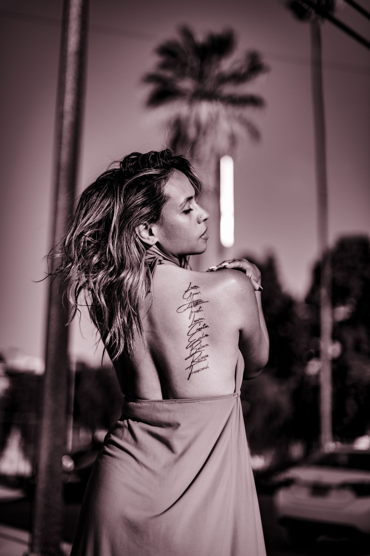 A black and white photo series showing a person with windswept hair against palm trees at sunset.