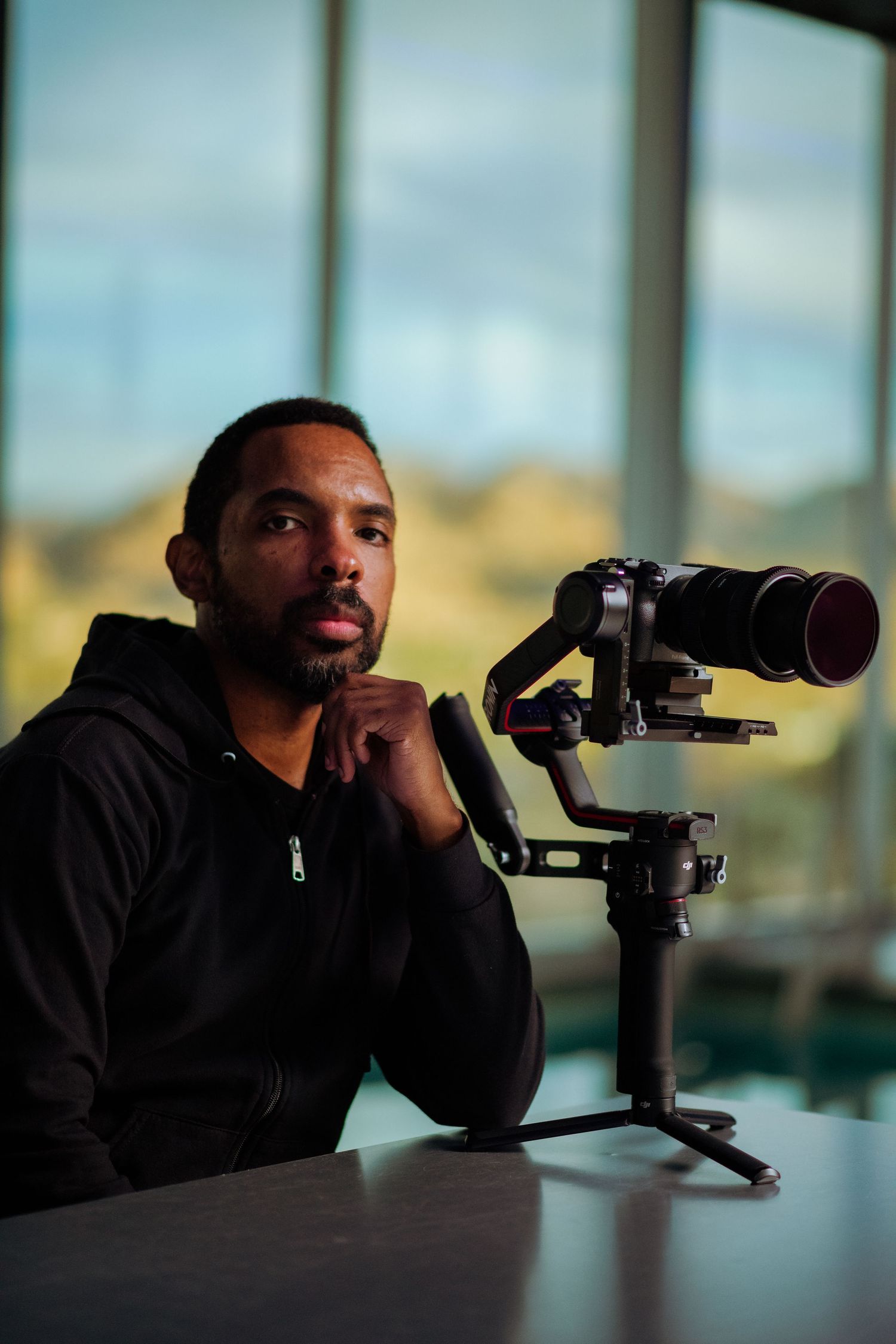 Person using a spotting scope while leaning on surface in dark lighting conditions.