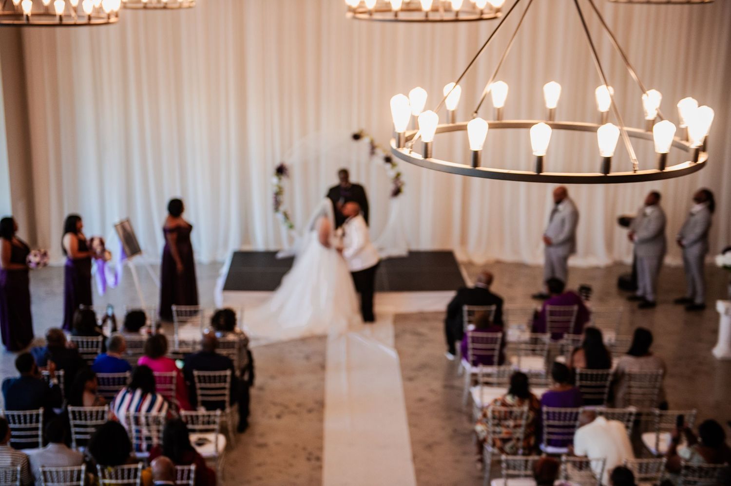 Elegant wedding ceremony space with white drapes and illuminated chandeliers.