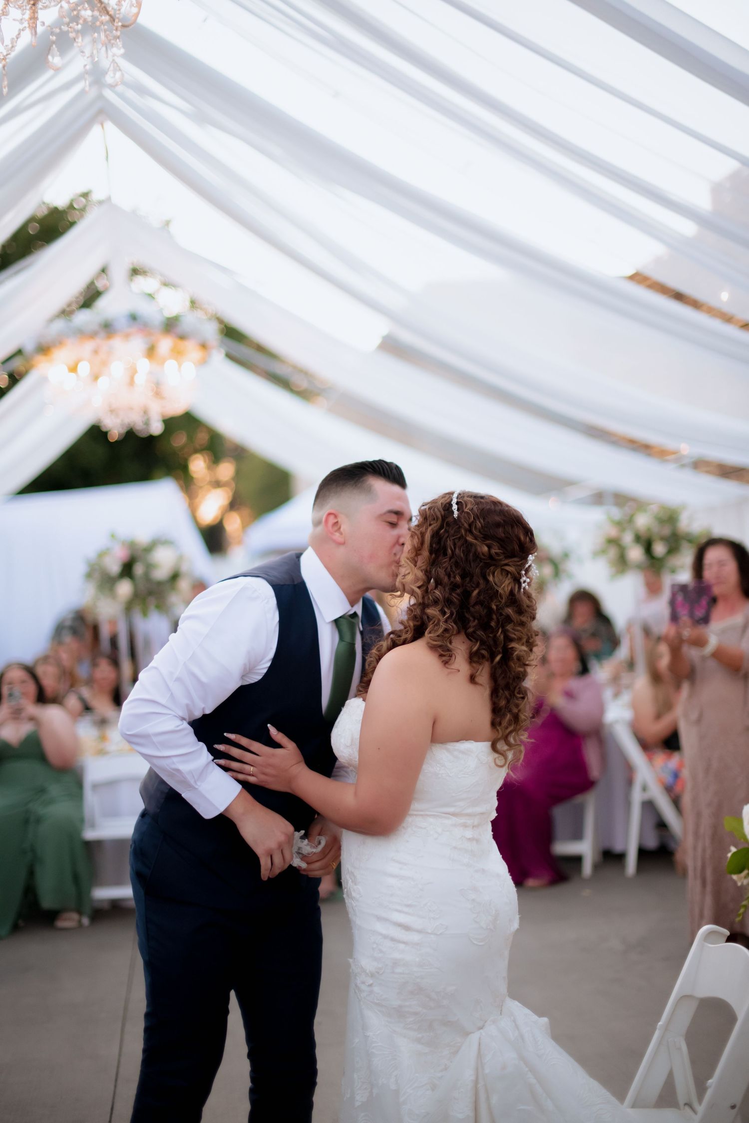 A romantic moment captured at a wedding reception under elegant white tent draping.