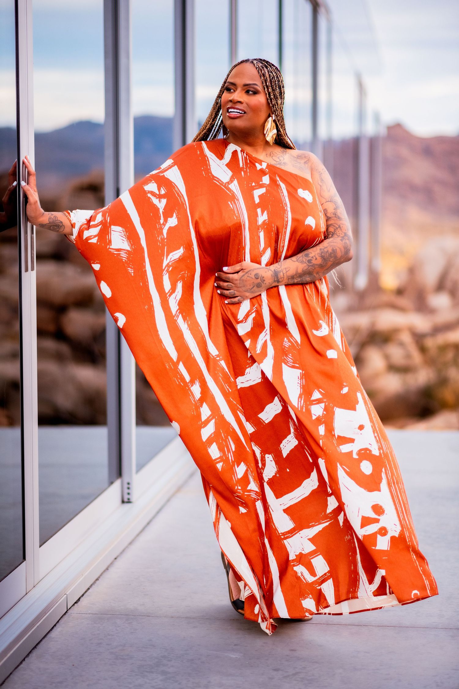 Orange and white patterned dress flowing in breeze against desert mountain backdrop.