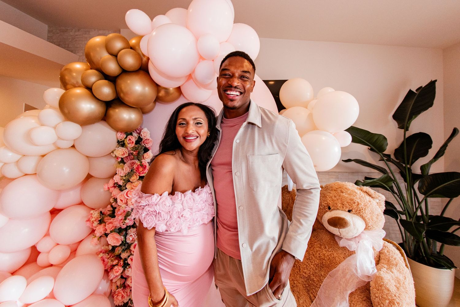 A baby shower celebration decorated with pink and gold balloons and elegant party decor.