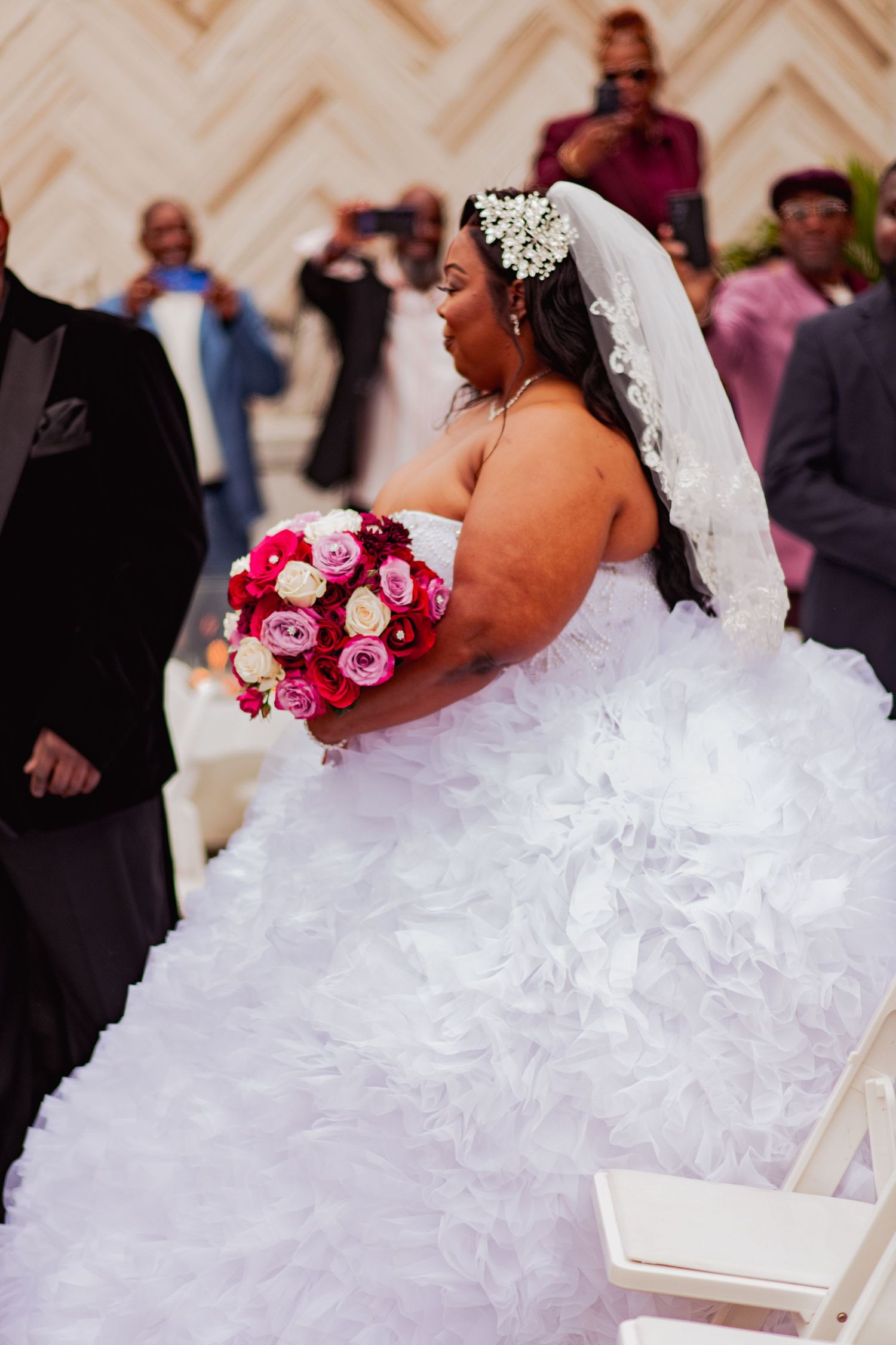 A stunning white ruffled wedding dress with a dramatic full skirt contrasts against burgundy bridesmaids dresses.