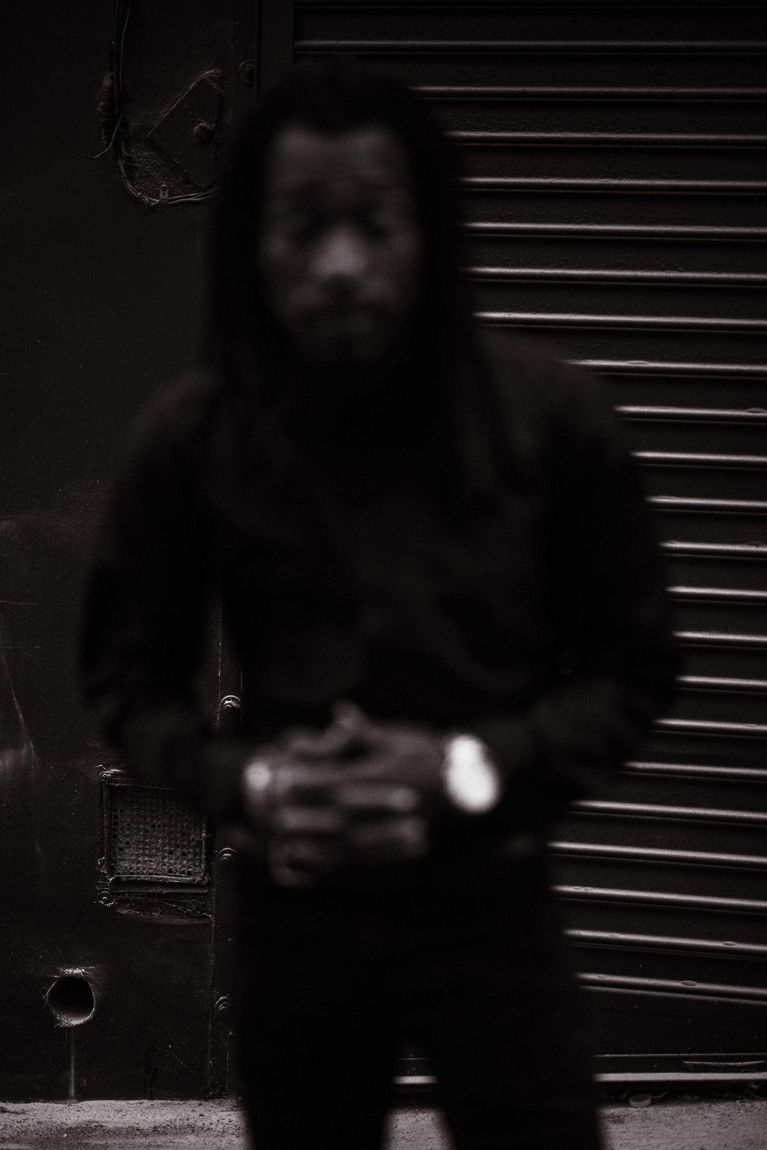 Dark silhouette figure standing against black background with horizontal lines.