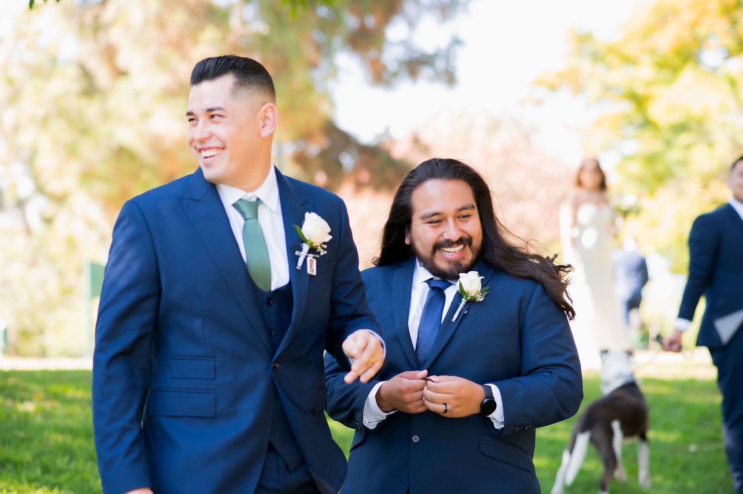 Groomsmen laugh and joke together during outdoor wedding photoshoot.