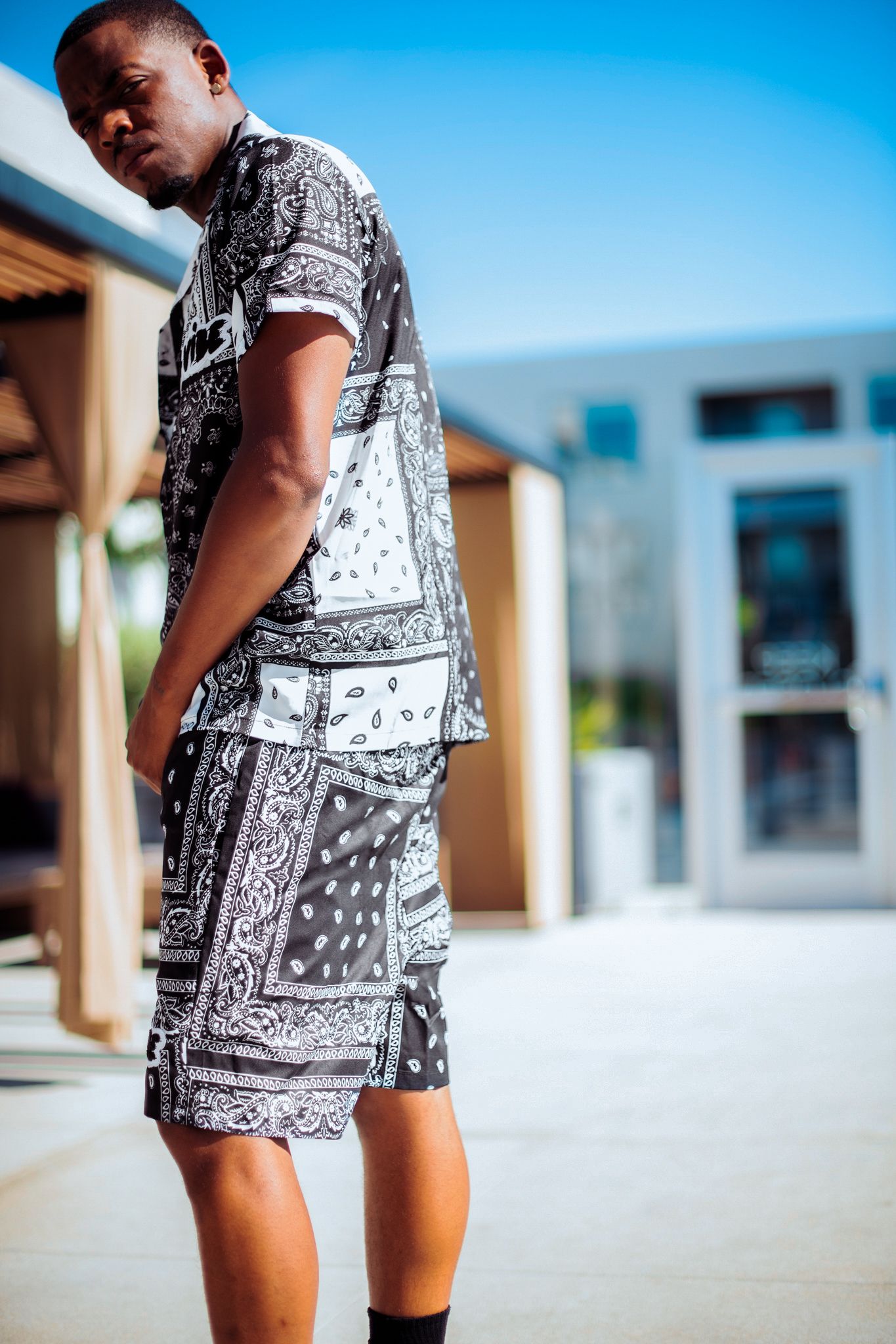 Person modeling bandana print coordinated outfit against bright blue sky background.