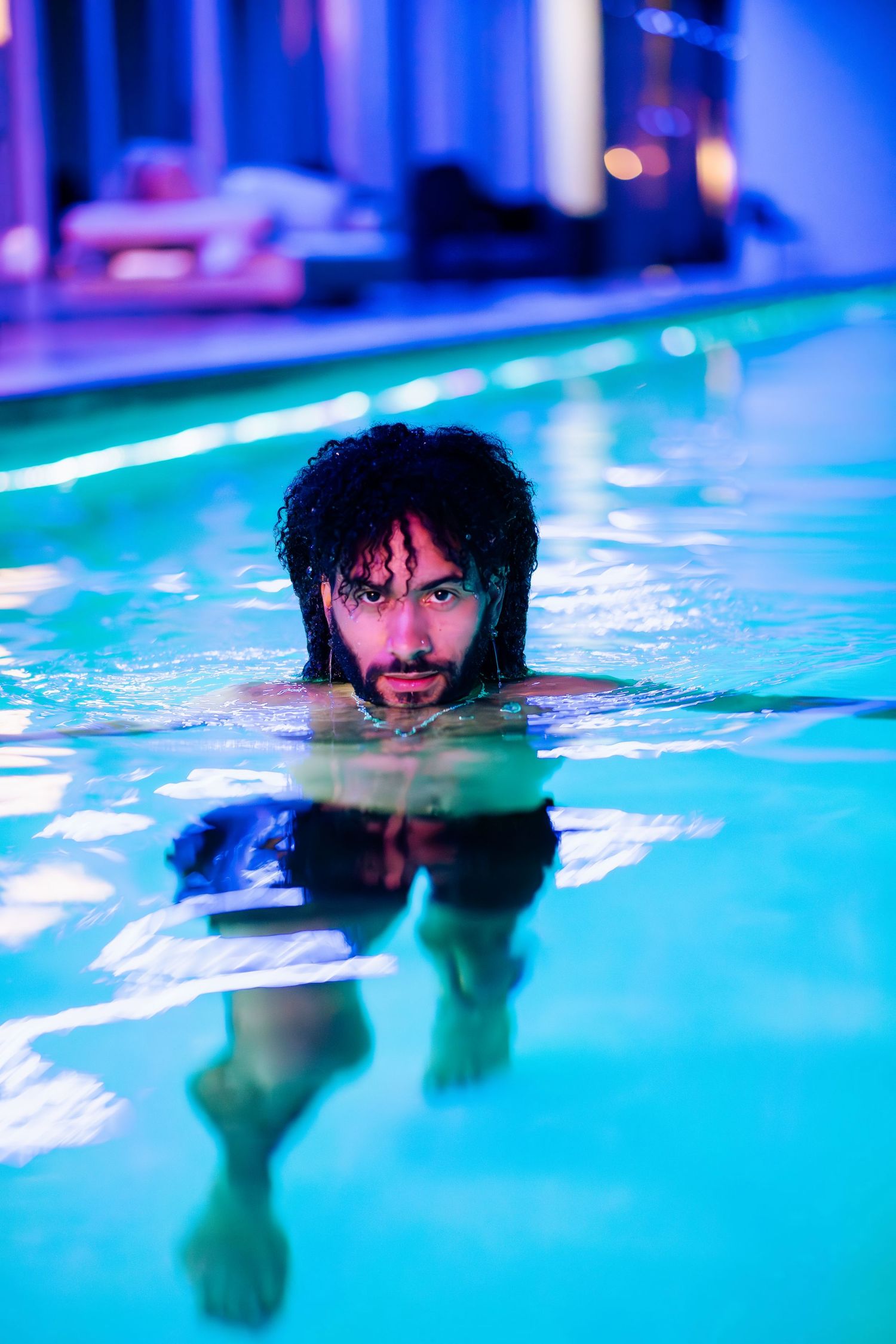 Legacy Doherty Creative swimming pool portrait at the Invisible House with blue lighting and partial face showing above water surface.