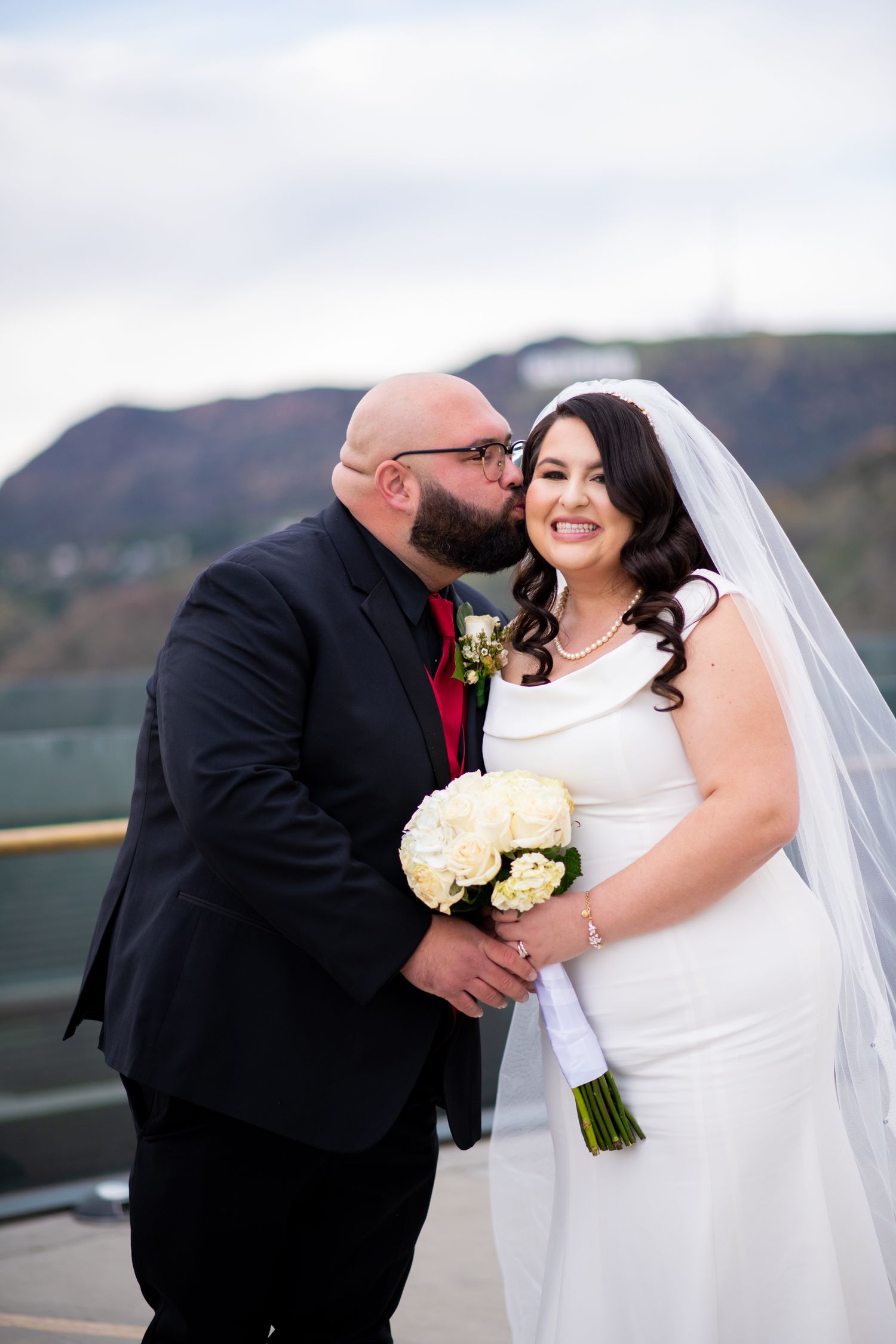 A couple shares an intimate moment during their outdoor wedding celebration with mountain scenery in the background.