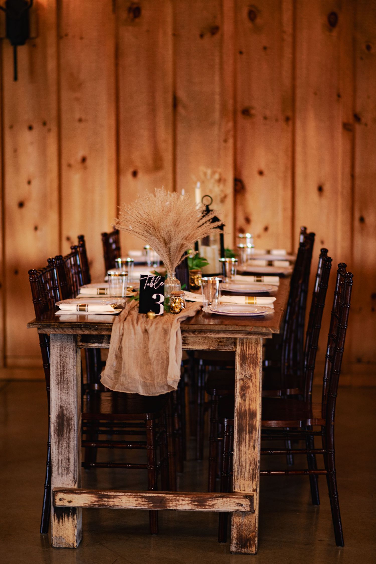 Rustic wooden tables and chairs set up for dining in a cozy restaurant with pine wood paneled walls.