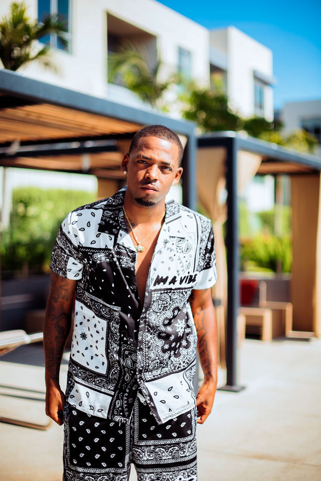 Person wearing black and white bandana print matching set poses outdoors in sunny setting.