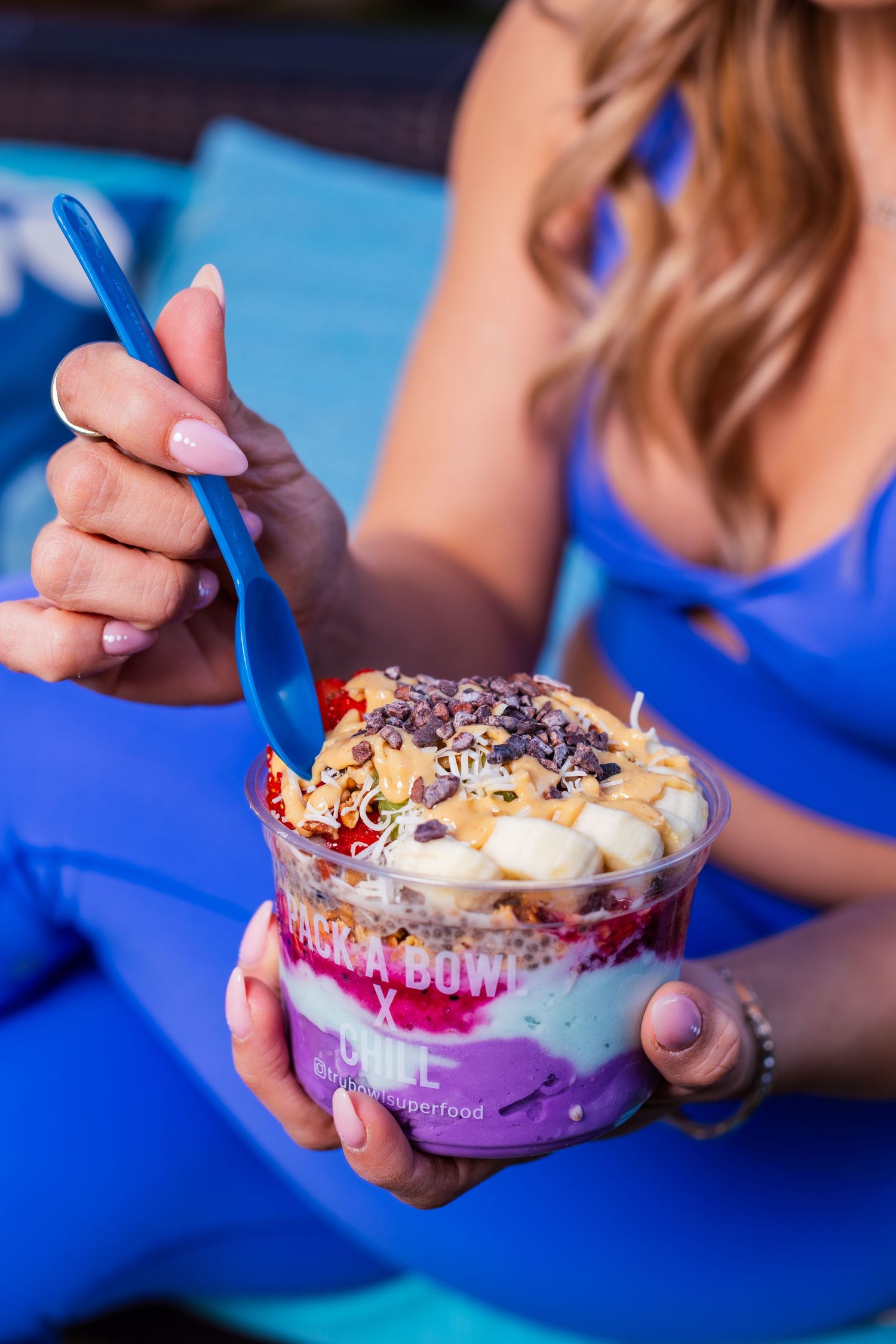 Close-up of colorful acai bowl with fruits and toppings being enjoyed outdoors.
