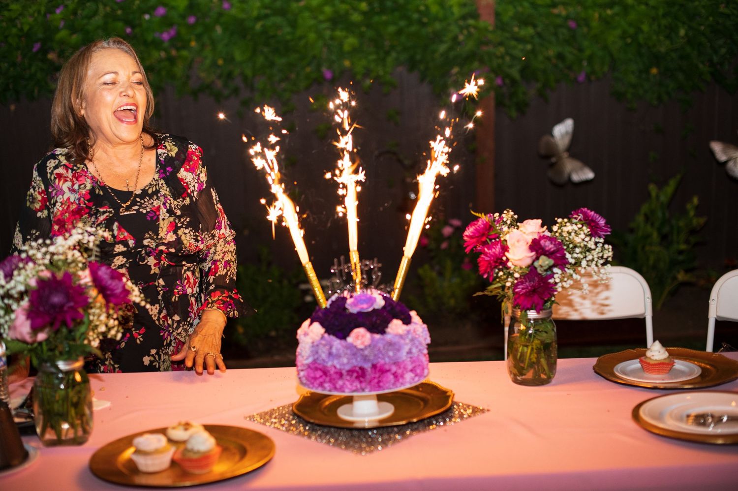 Birthday celebration table with sparklers and purple cake decorations glowing in evening light.