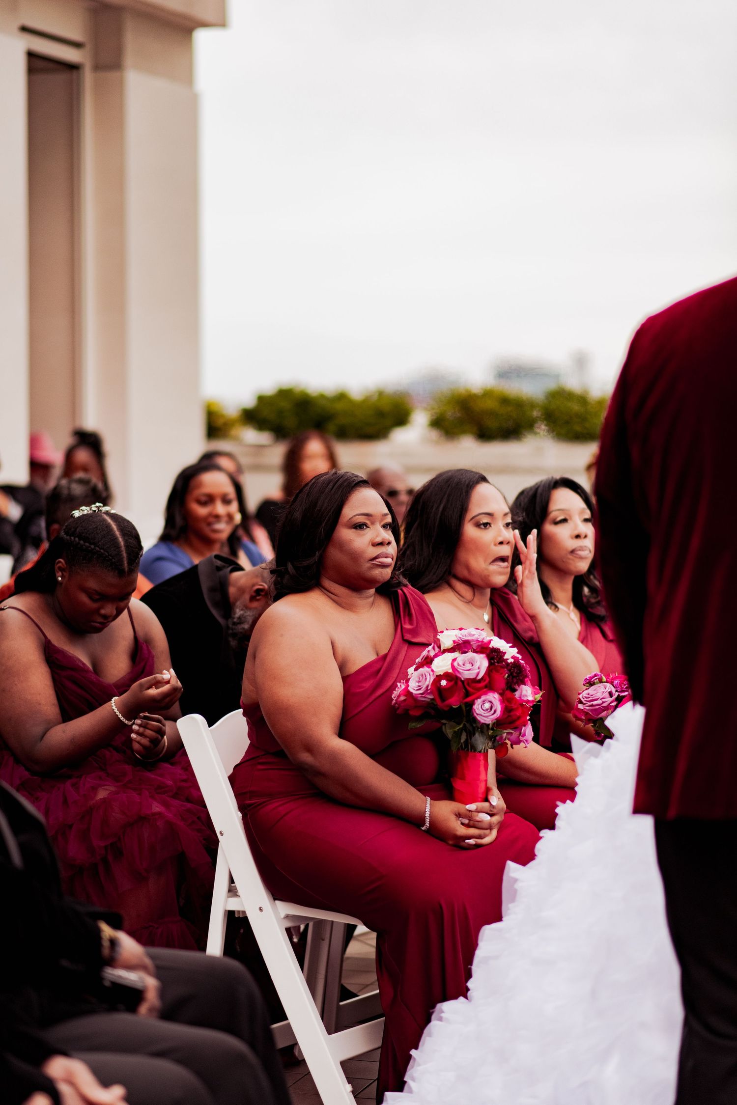 Wedding guests seated in white chairs watch the ceremony against a modern architectural backdrop.