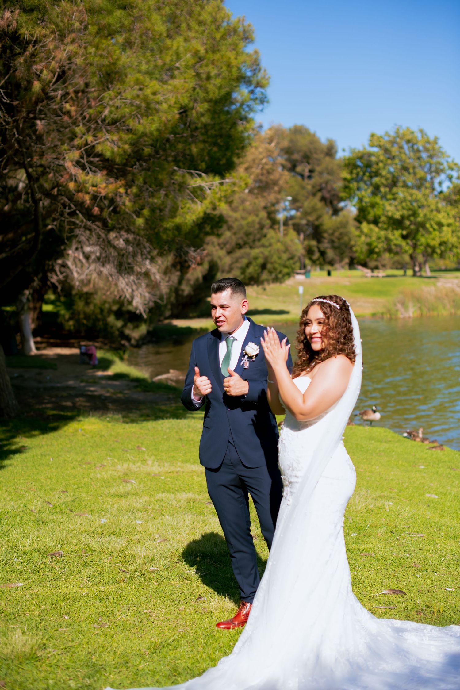 Joyful wedding moment captured outdoors with lake and park scenery.