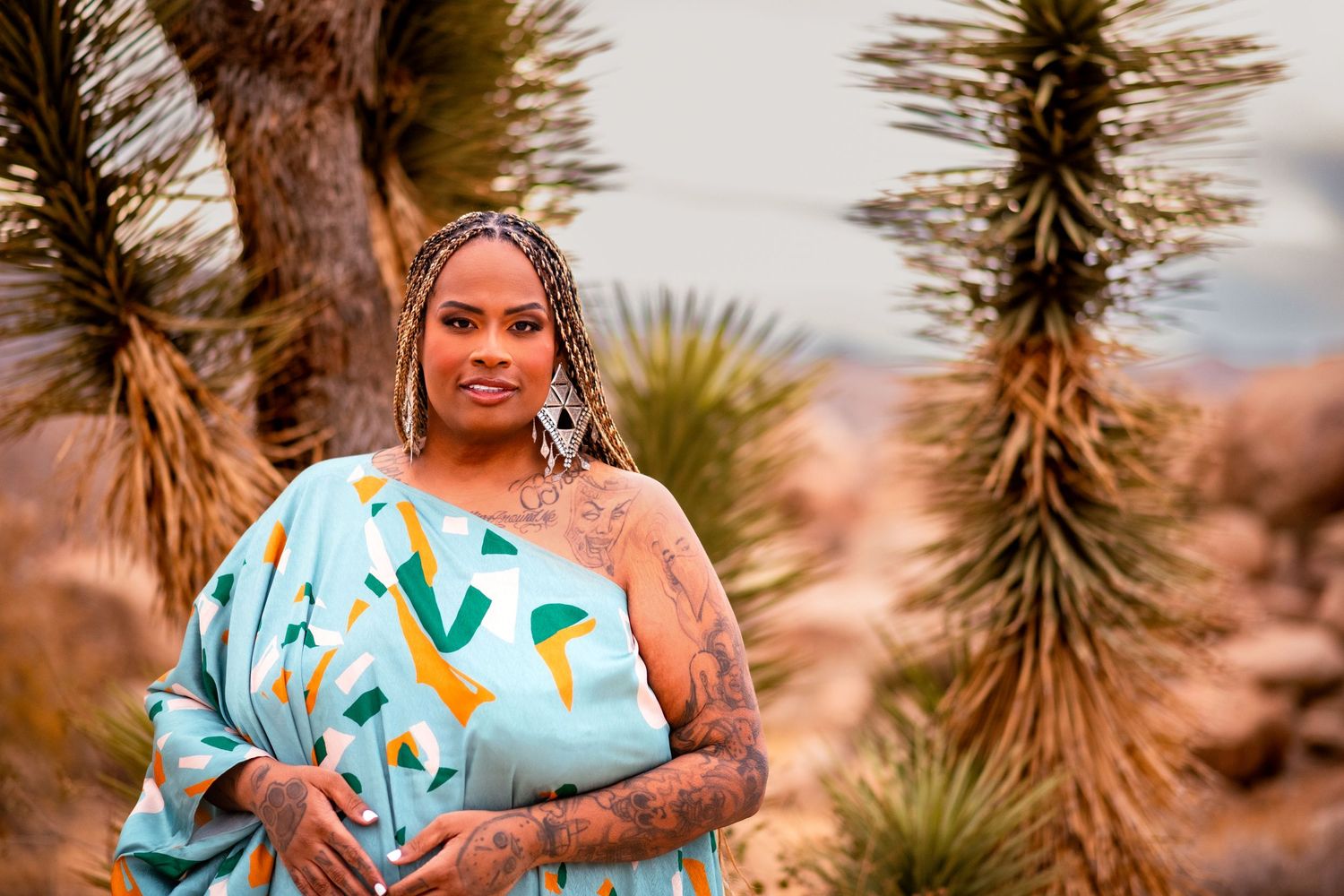 A flowy turquoise patterned dress is featured in a desert photoshoot with yucca trees.