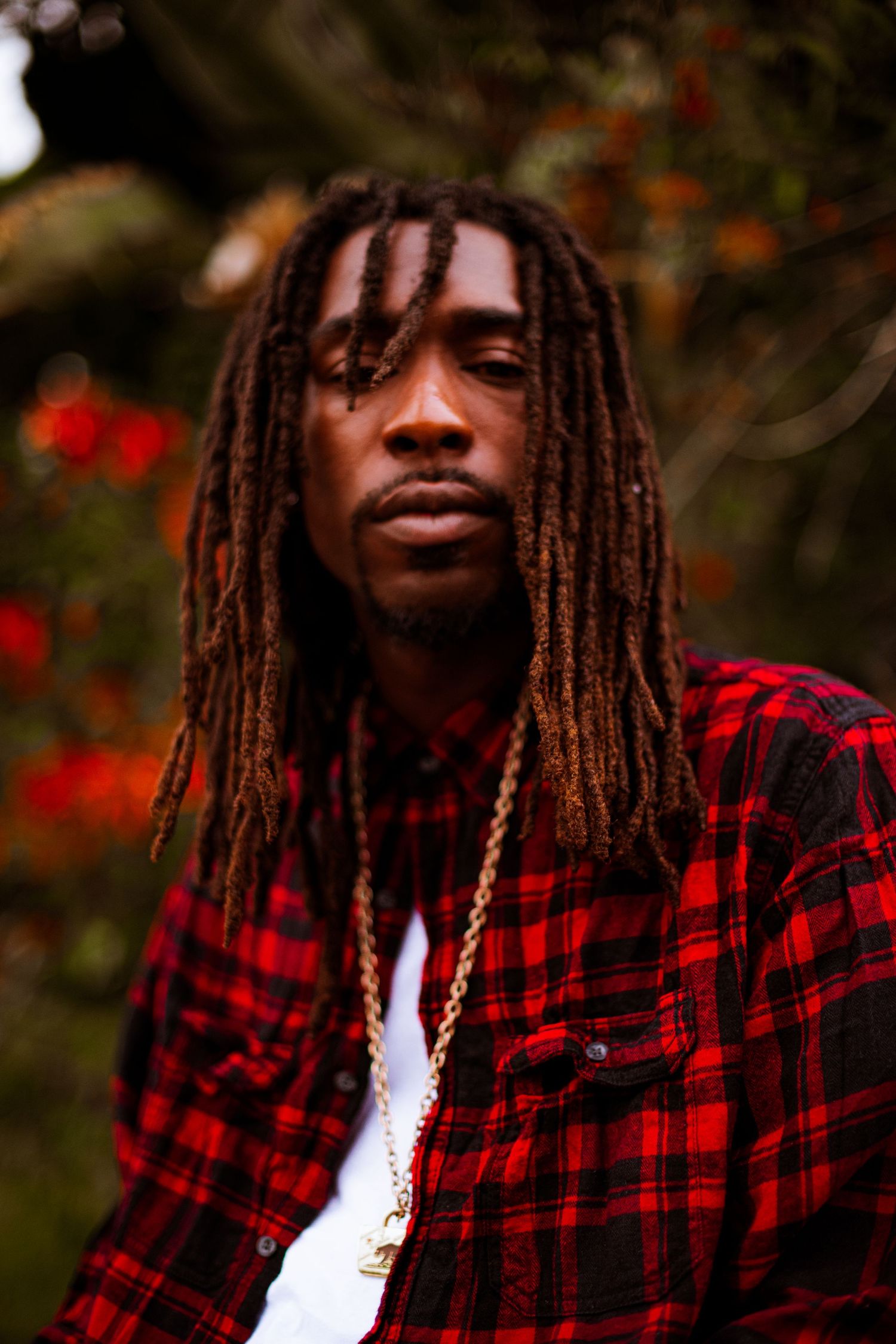 King'Juan HollyHood DiceTheReaper
 with long dreadlocks wearing red plaid shirt outdoors with natural background. Dope Photo shoot Rapper