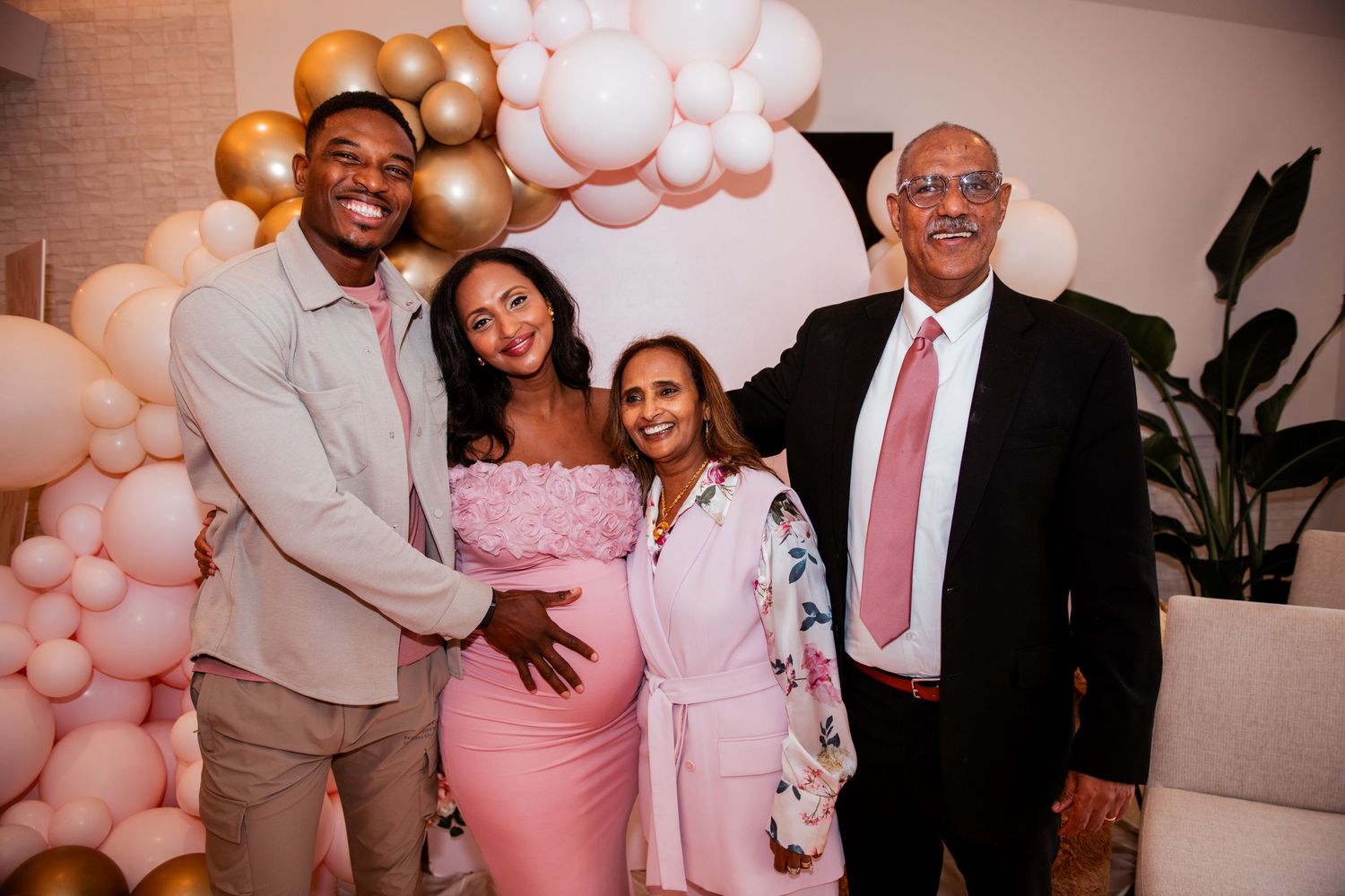 Formal gathering with pink and gold balloon decorations in the background.