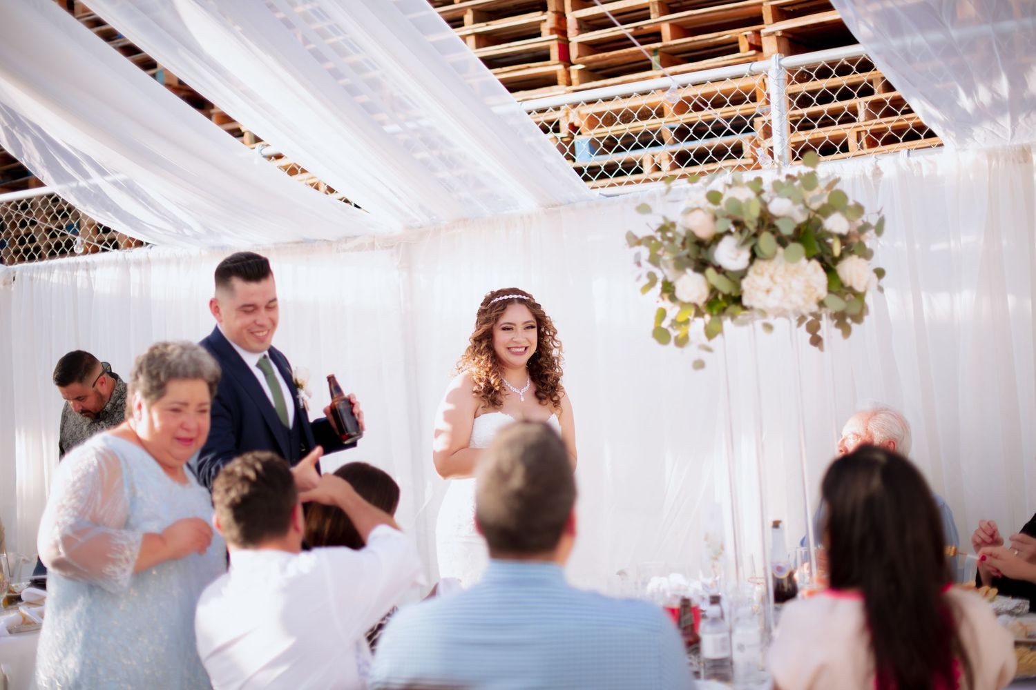 Wedding reception venue with white draped ceiling and hanging floral decorations.