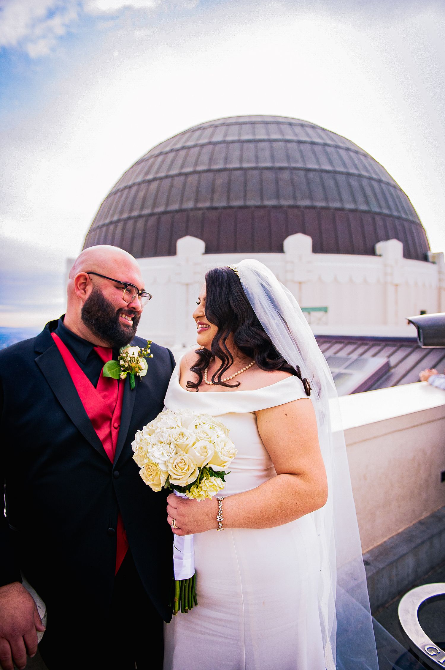 A romantic wedding moment captured on a rooftop with domed architecture and cloudy skies in the background.