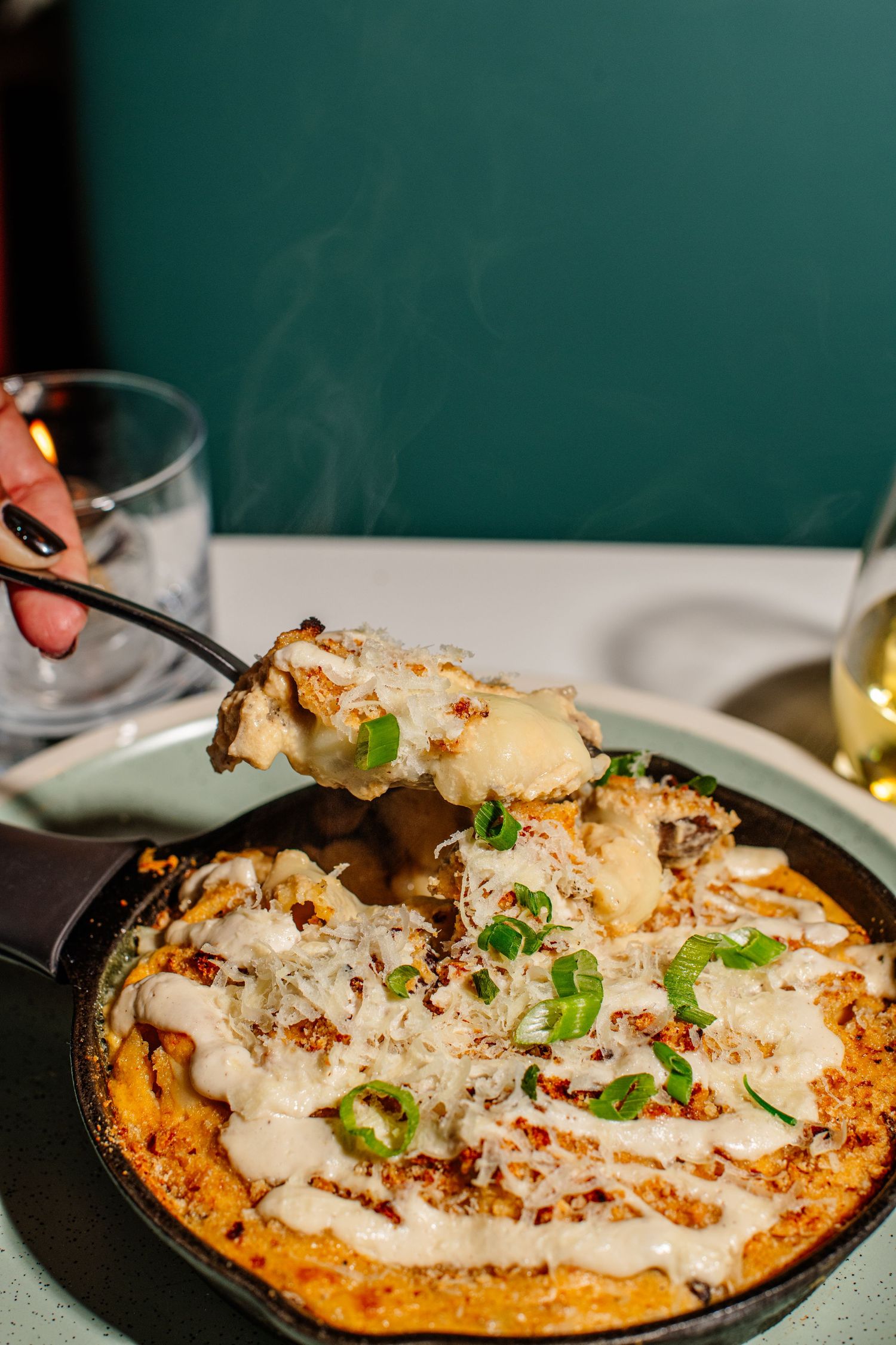 Creamy white sauce drizzled over a crispy flatbread pizza topped with fresh herbs in a cast iron skillet.