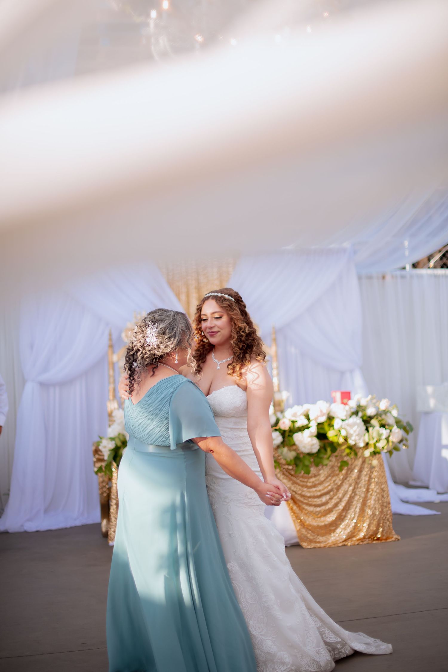 Emotional dance moment between two people at wedding reception with mint dress and white gown.