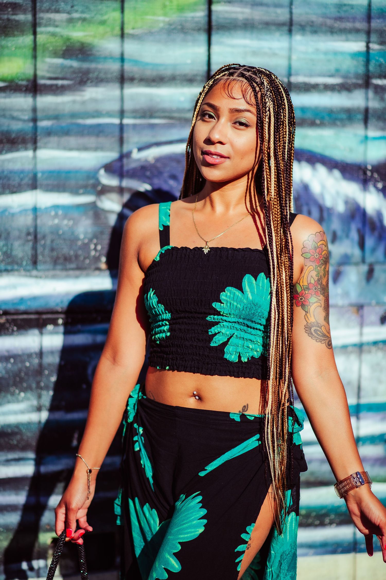 Stylish summer outfit featuring bold turquoise palm prints on black fabric with urban backdrop.
