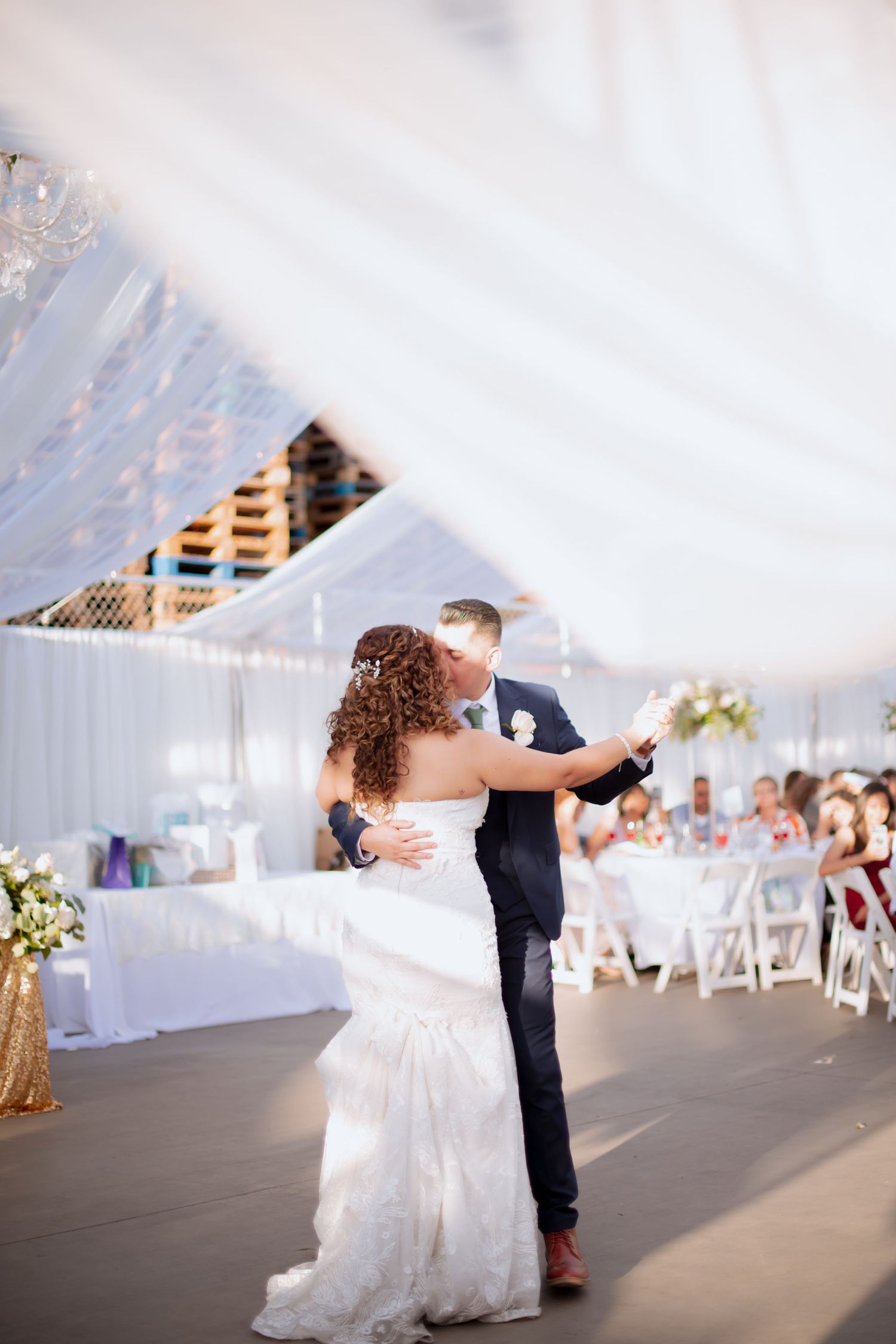 A couple dips during their first dance at a beautifully decorated outdoor wedding reception.