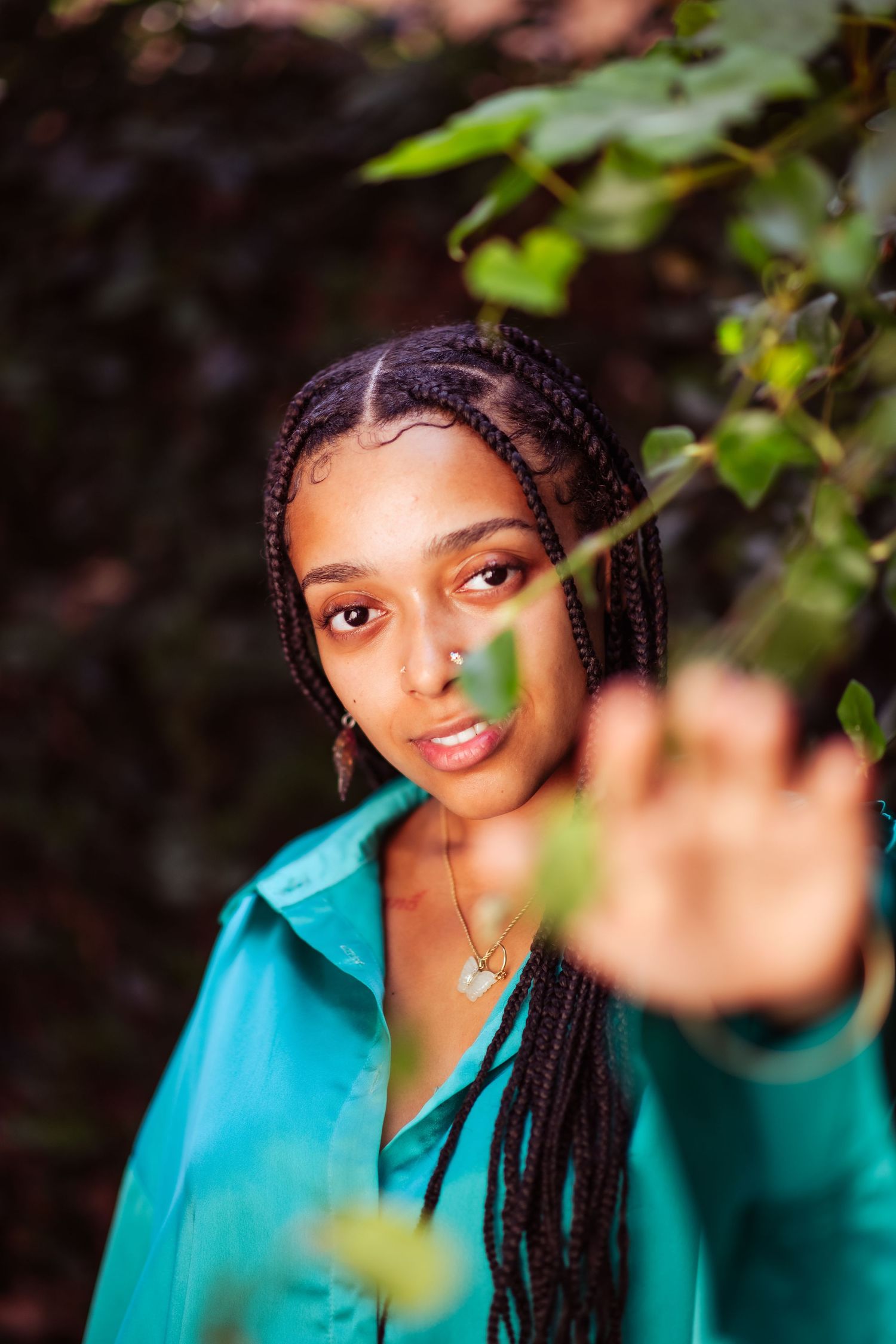 Artistic outdoor portrait series showing long braids and turquoise clothing with natural foliage elements.