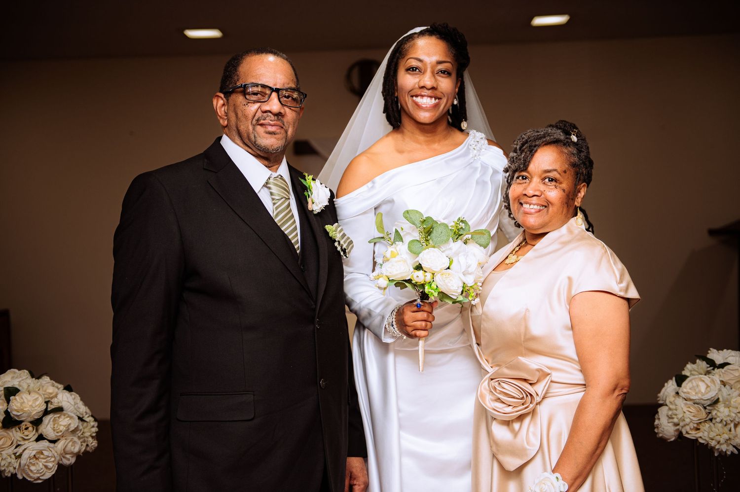 Wedding party group photo in formal attire with black suits and white dresses.