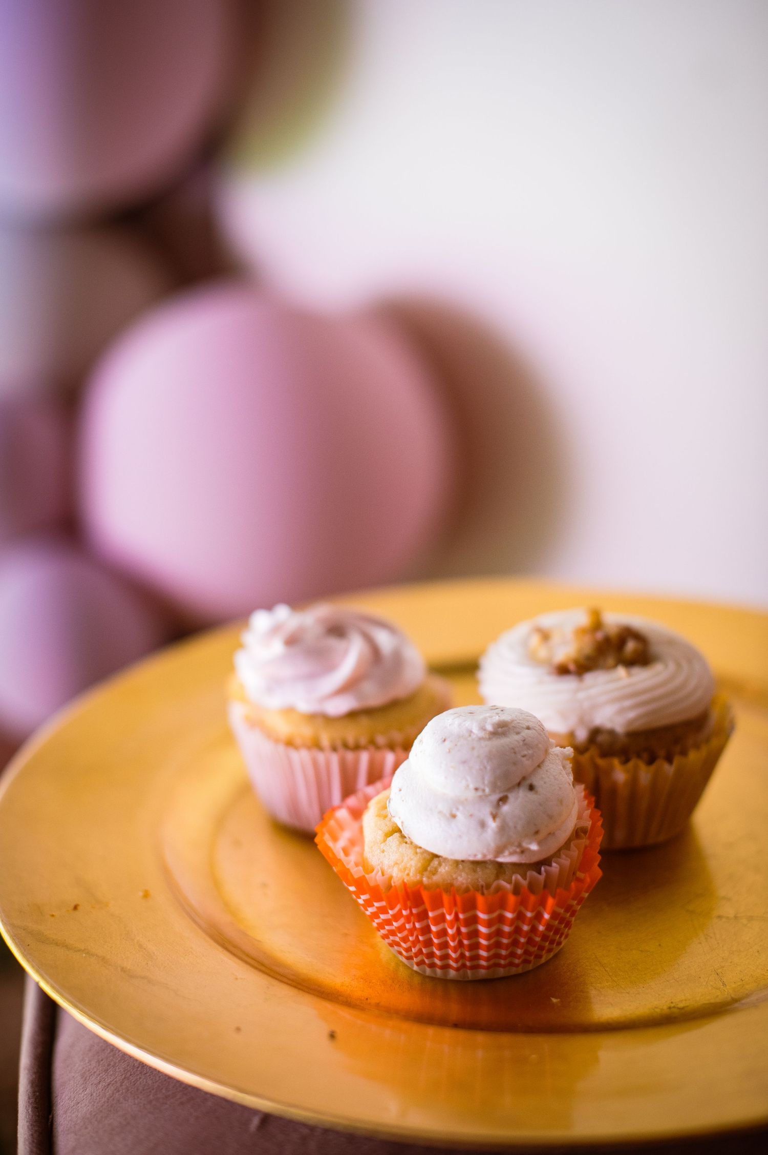 Pink frosted cupcake with whipped cream topping on a gold plate shown in a soft focus progression sequence.