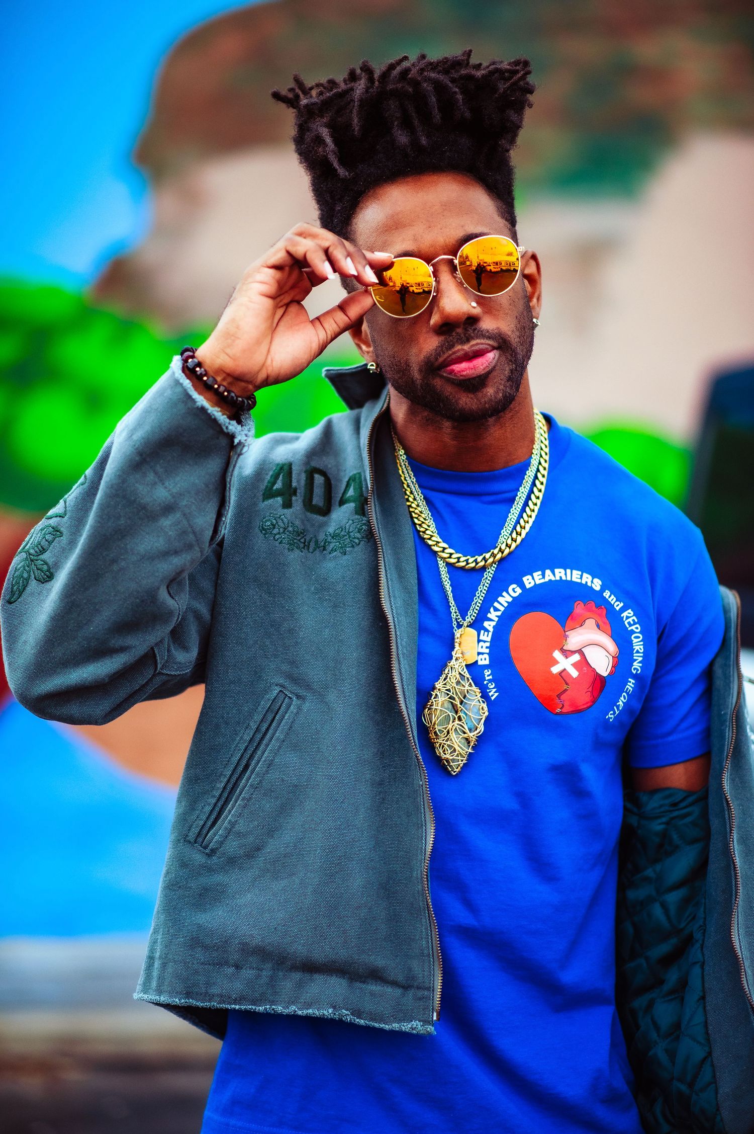 A LongLiveCzar close-up fashion series showing a stylish outfit with orange tinted sunglasses and a Breaking Beariers bright blue t-shirt.
