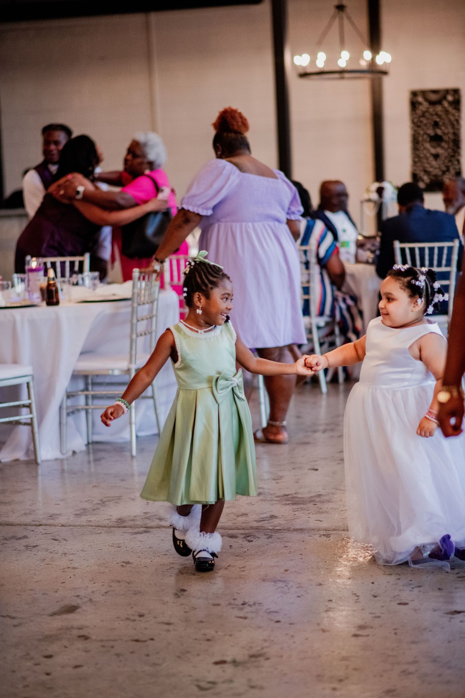 Young flower girls in mint green and white dresses playing at wedding reception.