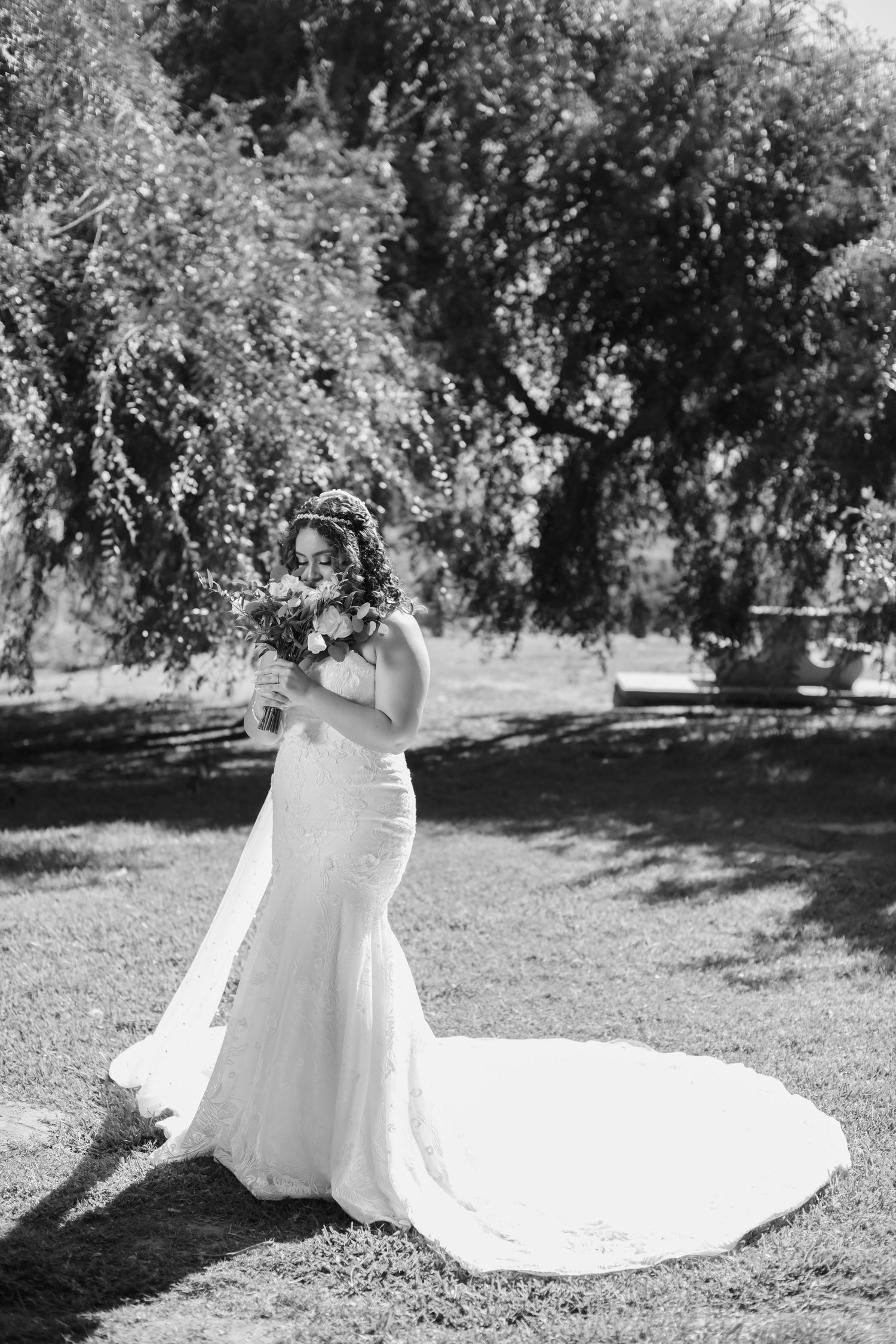 Elegant bridal portraits in black and white showing the sweep of a wedding gown in a garden setting.