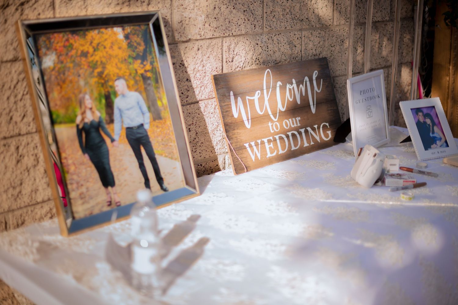 Winter wedding welcome sign with snowy pathway and stone wall backdrop.