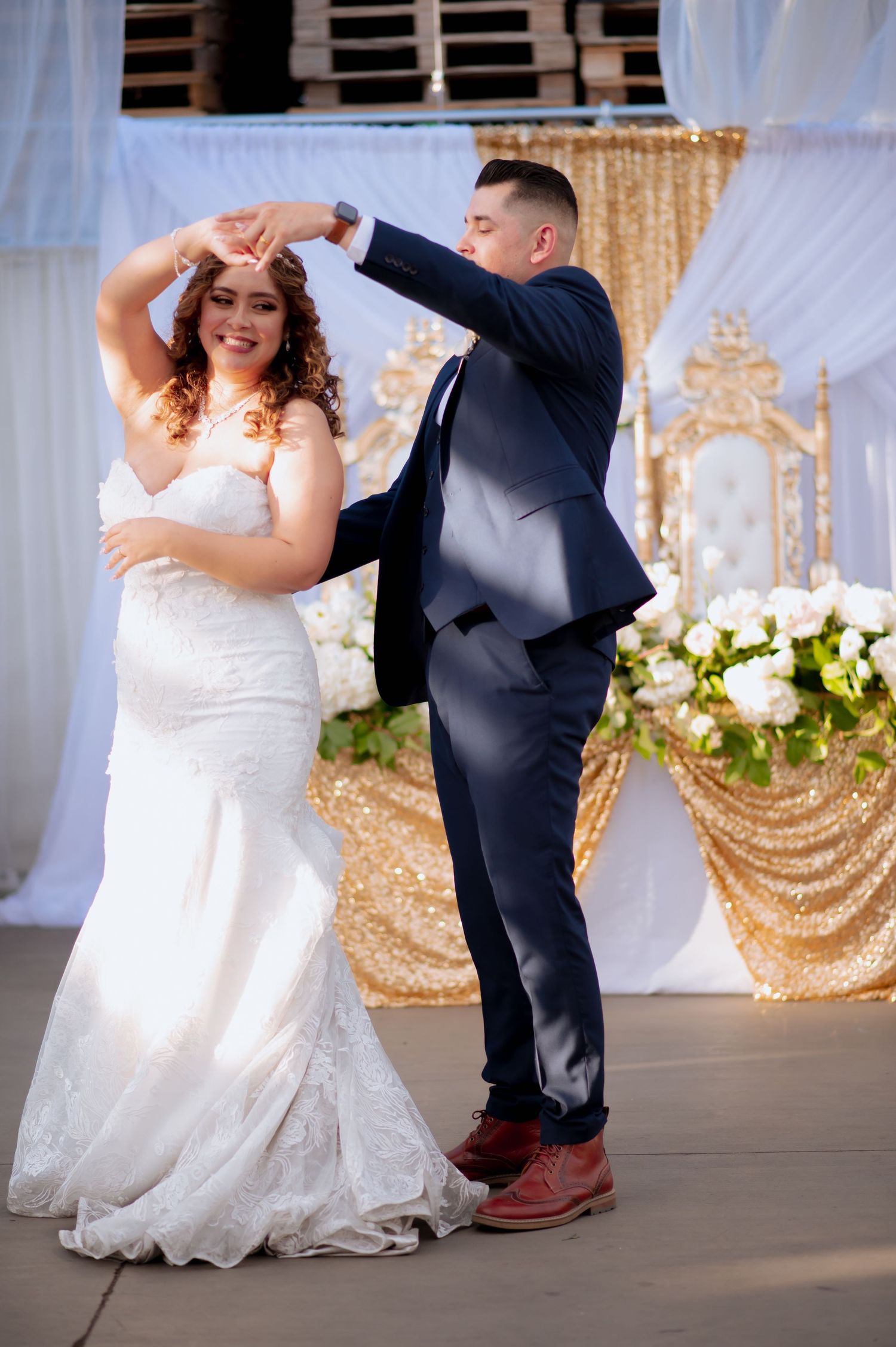 Dancing couple twirls on the dance floor under elegant white drapery and floral decorations.