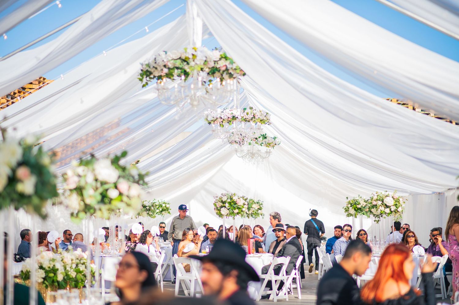 Elegant white draped tent ceiling with chandeliers for an outdoor wedding reception.