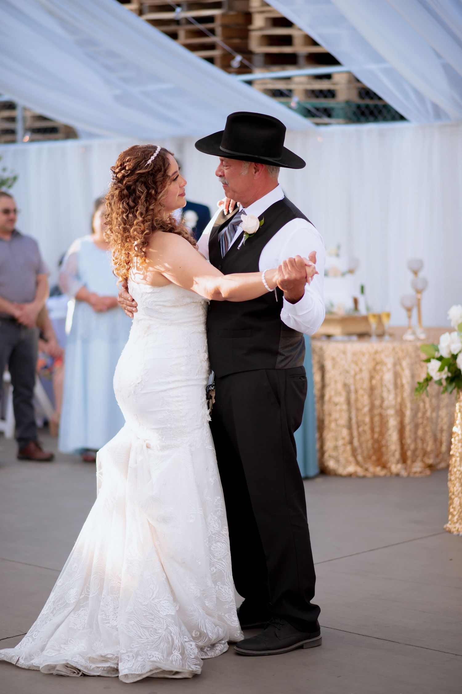 Father and daughter dancing at an elegant wedding reception under white fabric draping and sparkling chandeliers.
