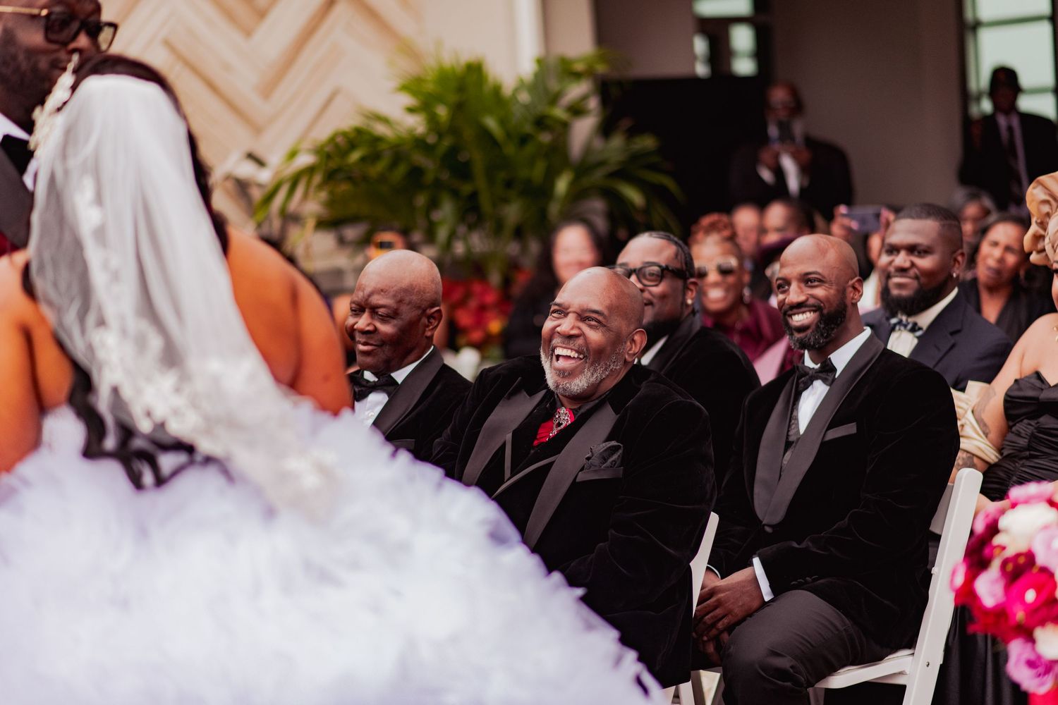 Wedding celebration with guests and wedding party wearing red and black formal attire.