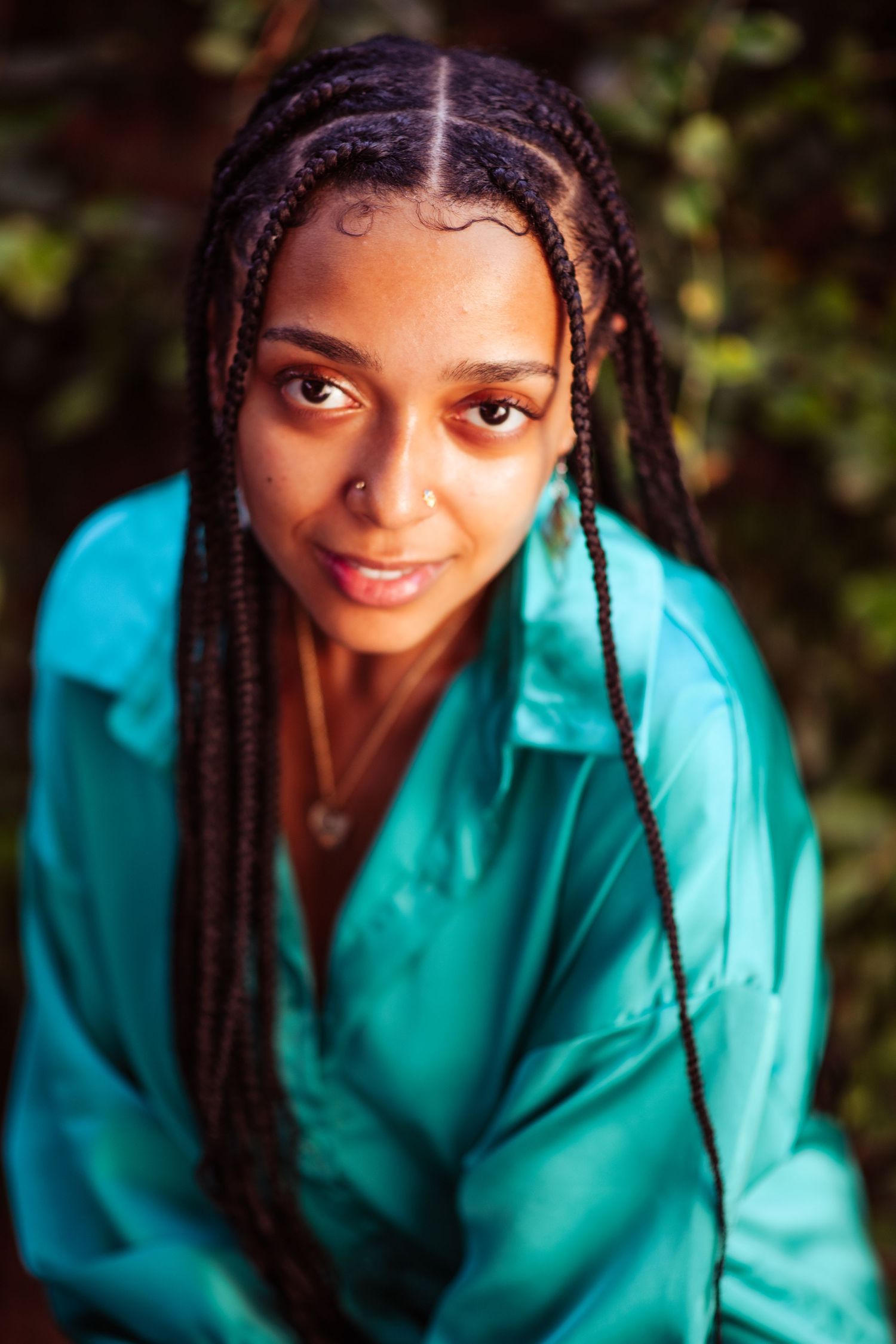 Person wearing bright turquoise shirt posing for a portrait series with natural lighting.
