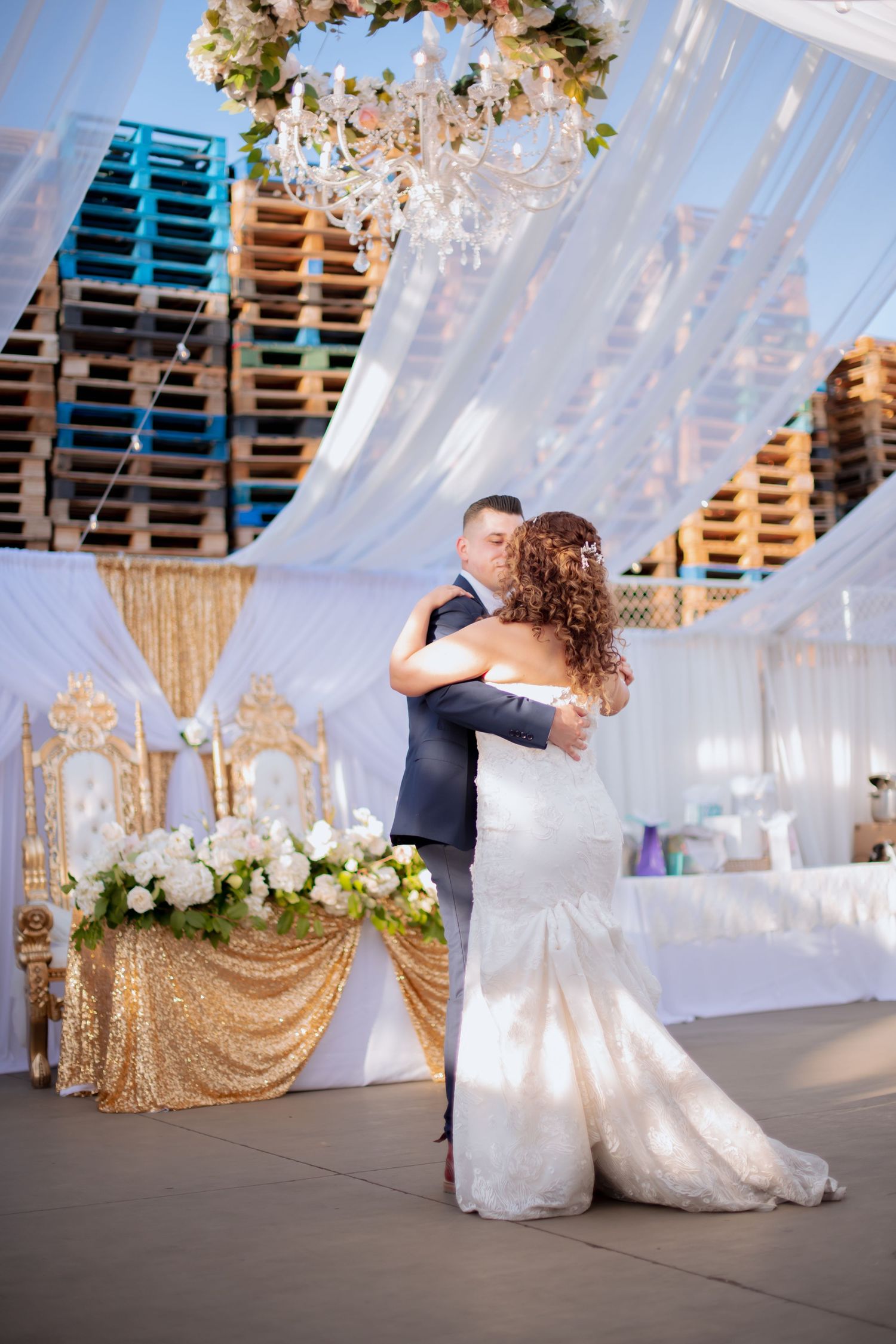 Couple performs romantic dance moves in a tent decorated with white drapes and gold sequin backdrops.
