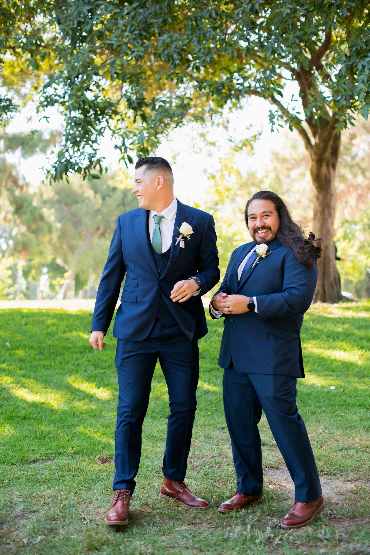 Groomsmen strike fun poses on grass during wedding photo session.