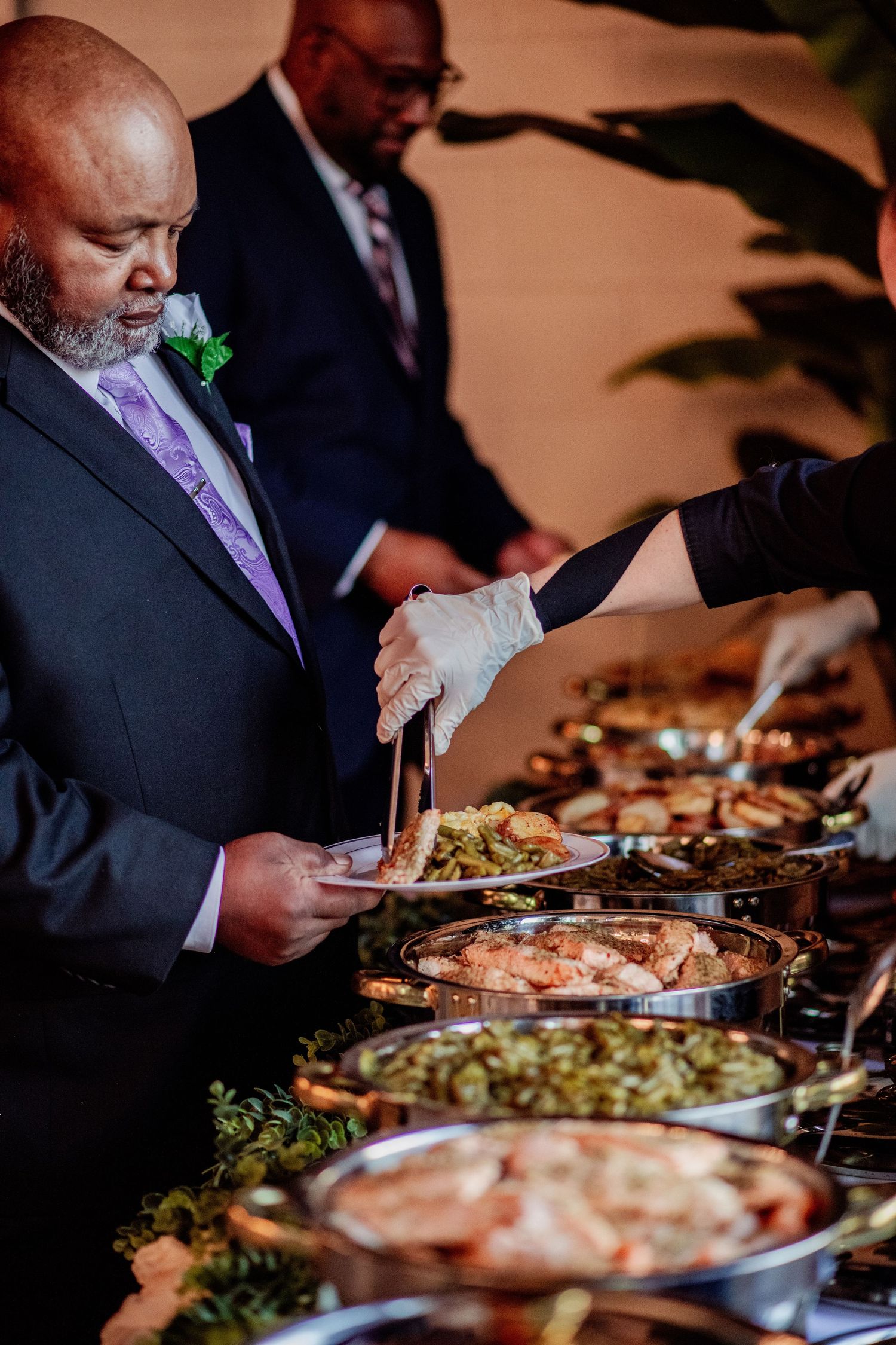 Wedding reception buffet with diverse dishes being served in metal chafing dishes.