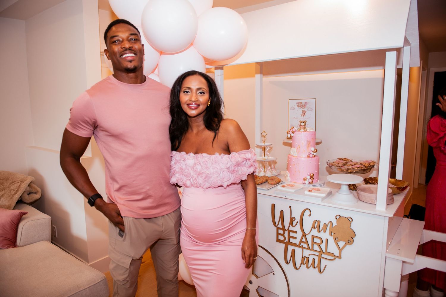 Pink and white themed party space with balloon garlands and teddy bear decorations.