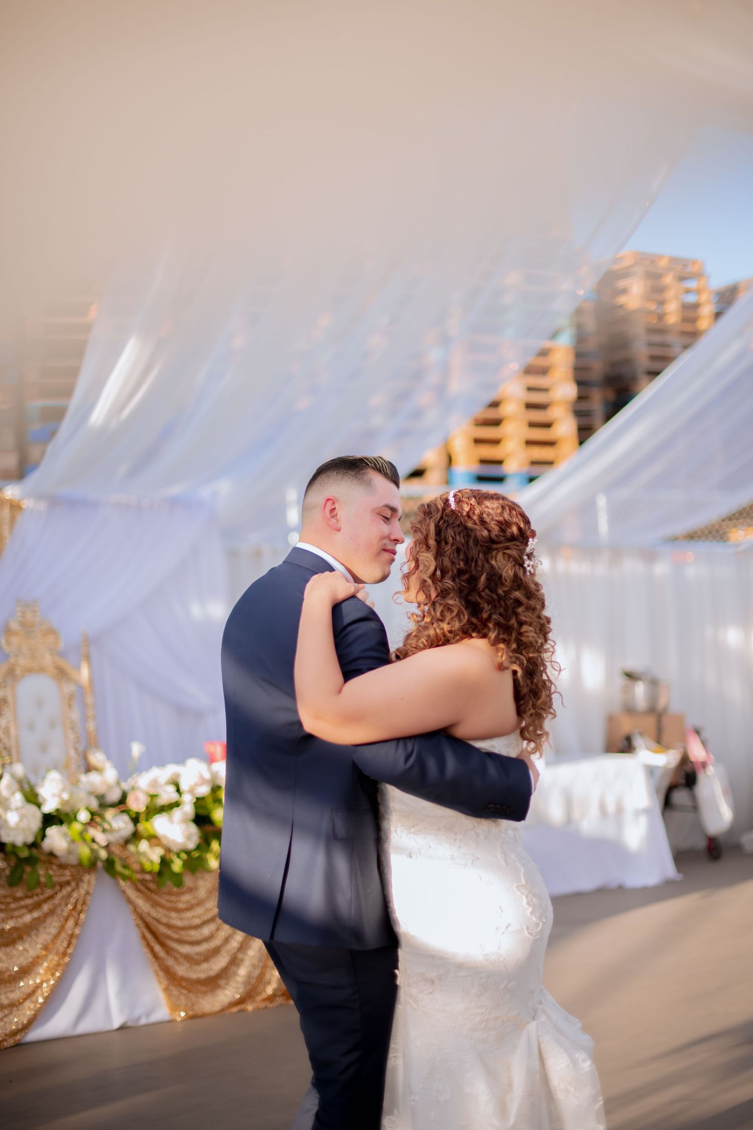 Couple sharing romantic dance moment at elegant white-draped wedding reception.