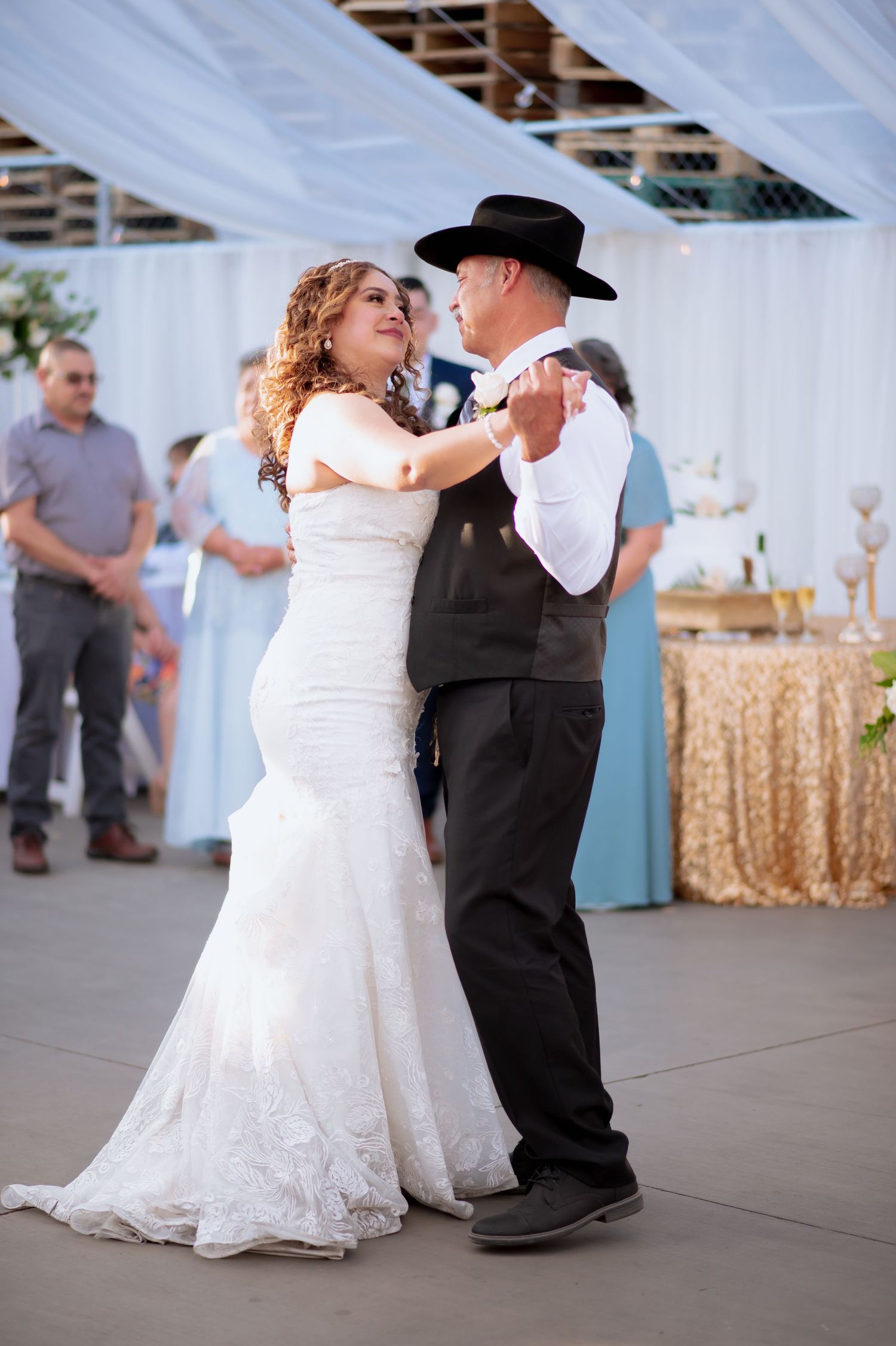Father and daughter sharing a special dance moment at a wedding reception with gold sequin decor.
