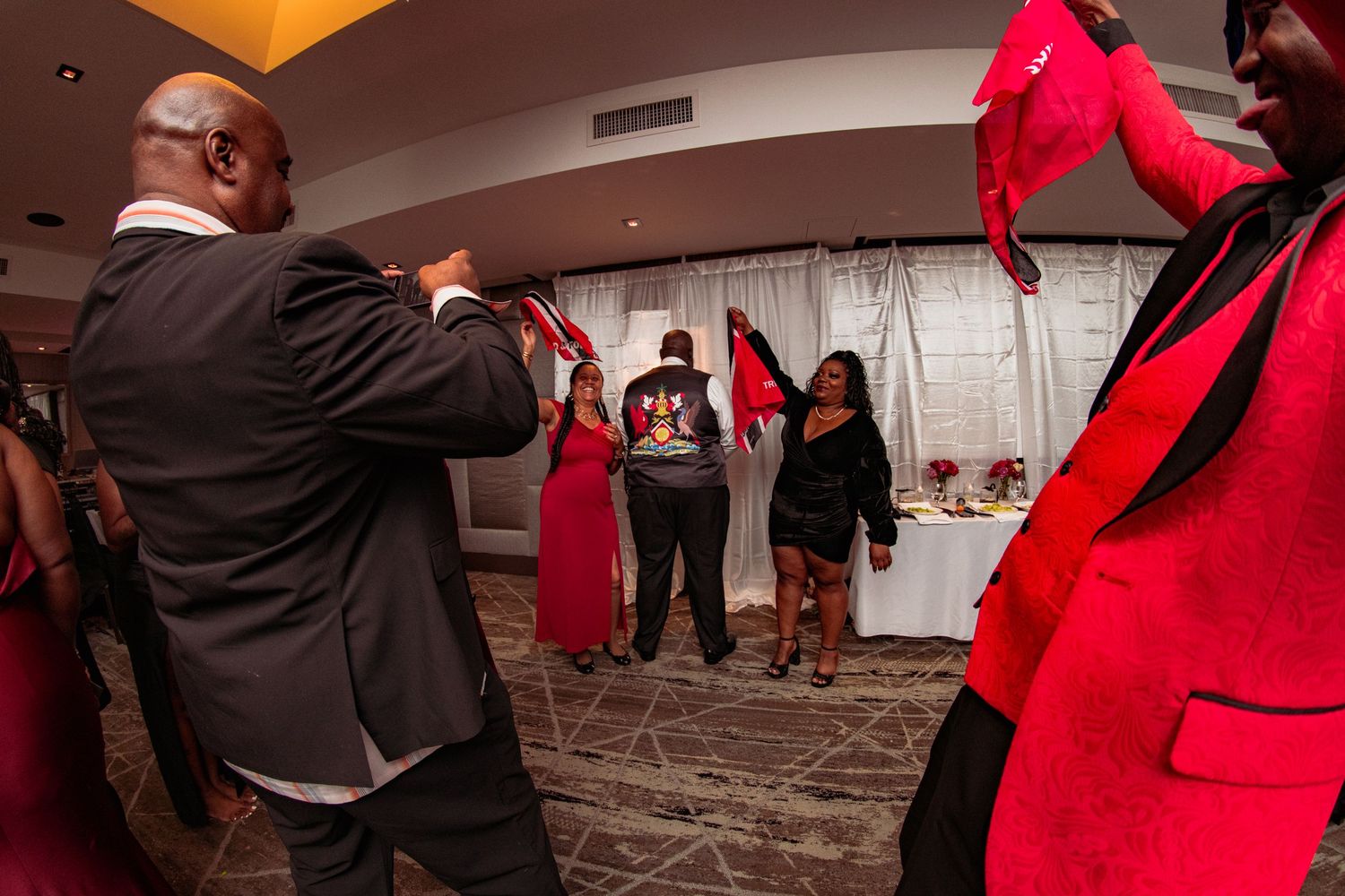 People in formal attire dance and celebrate at an indoor wedding reception.