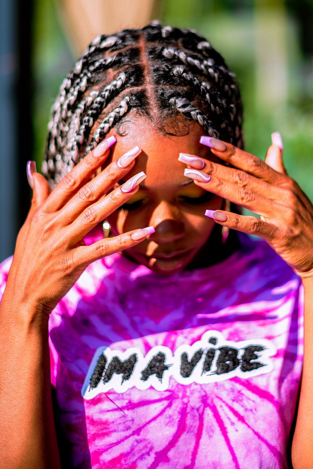 Close-up of hands with pink nails against tie-dye shirt with 'Im a vibe' text.