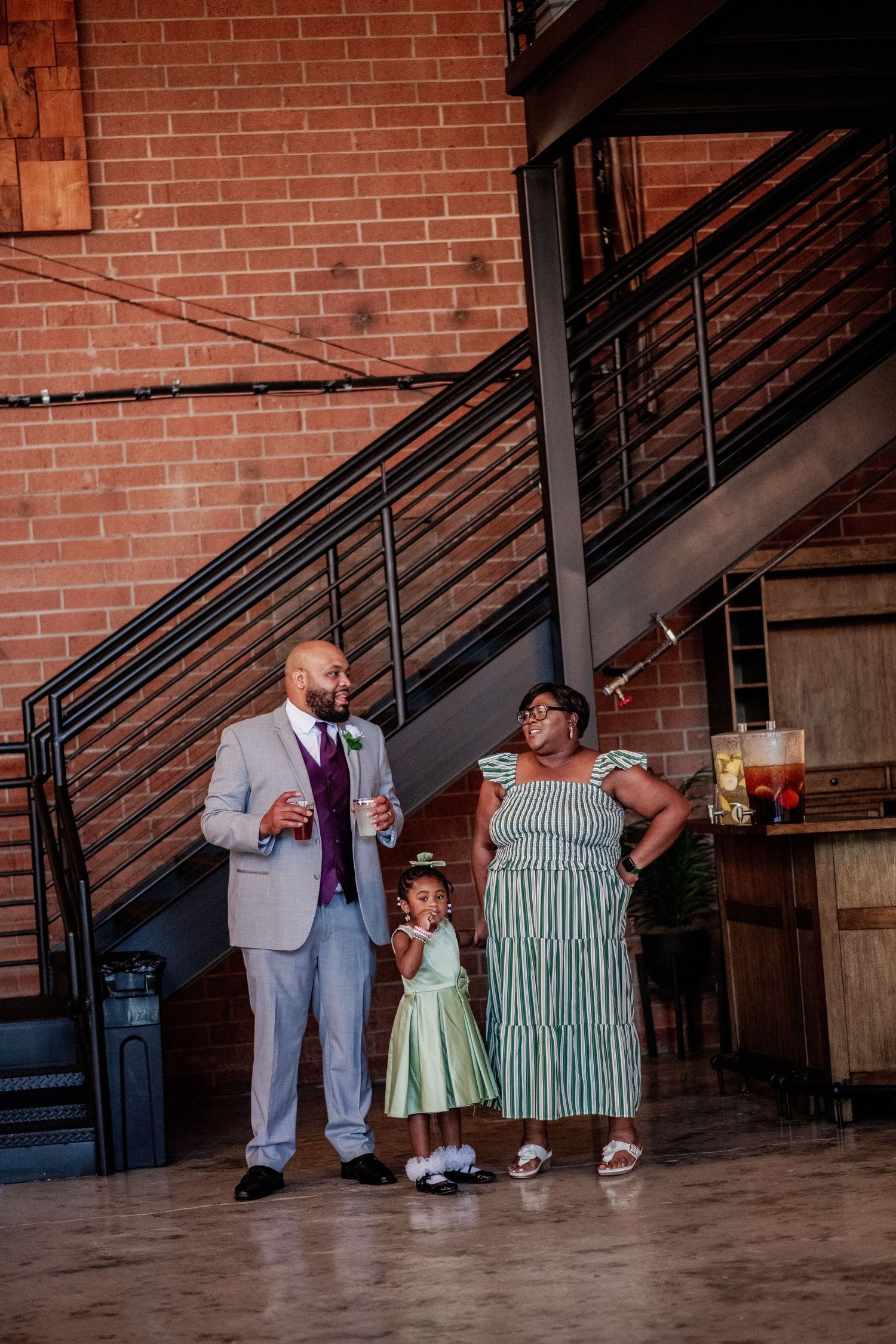 Wedding party members walking and posing along brick wall with staircase.